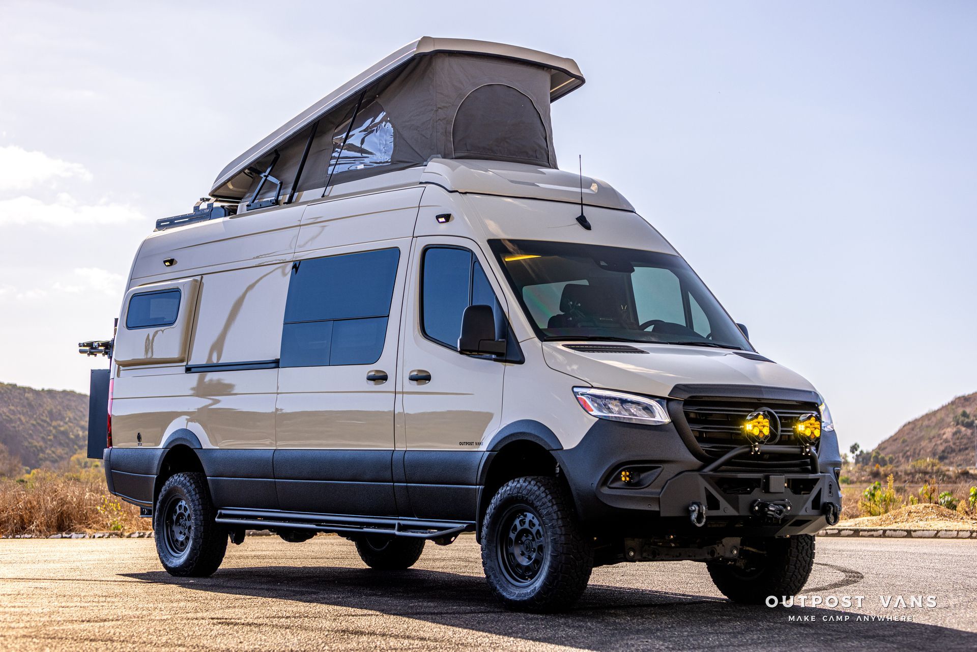 A white van with a pop up roof is parked on the side of the road.