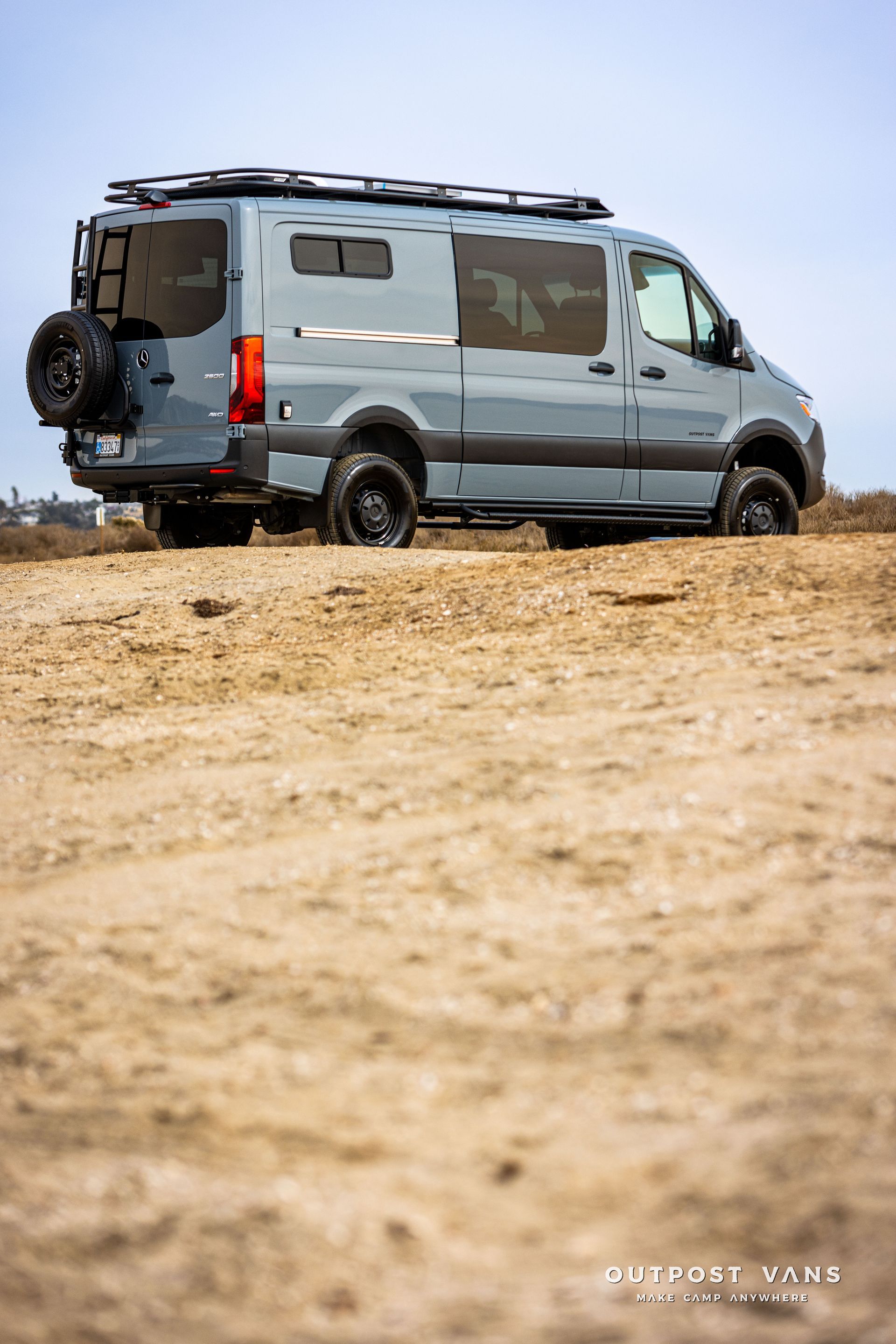 A van is parked on top of a sandy hill.