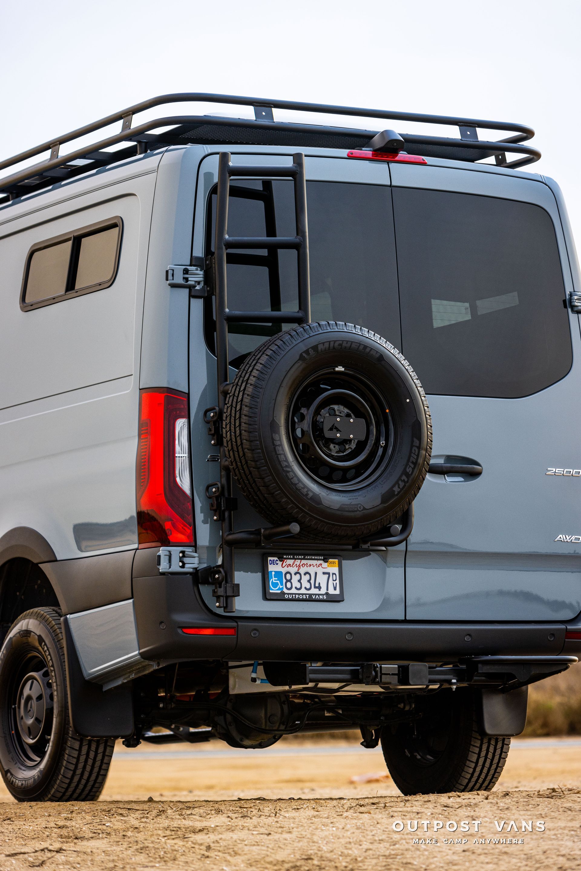 A gray van with a ladder attached to the back of it.