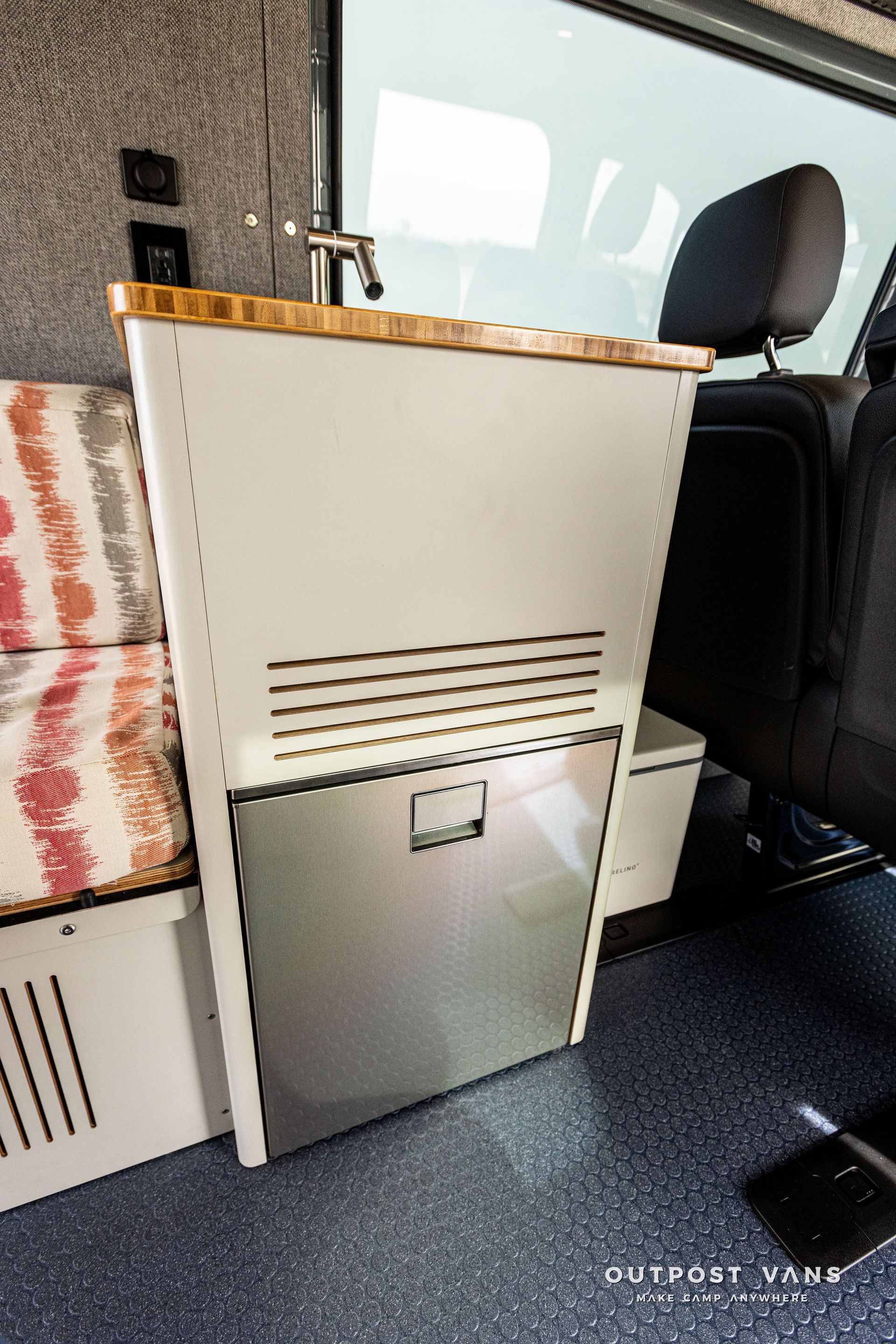 A stainless steel refrigerator is in the back of a van.