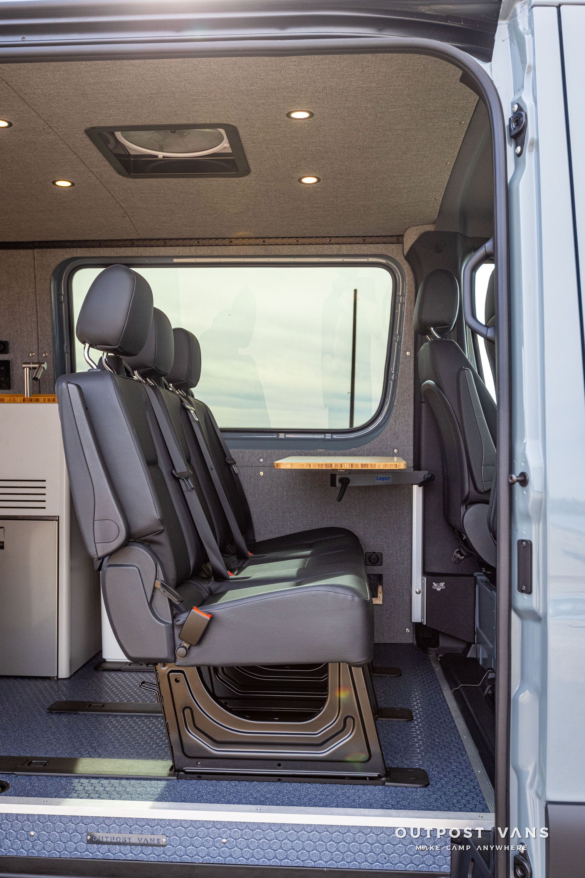 The back seat of a van with a table and chairs.