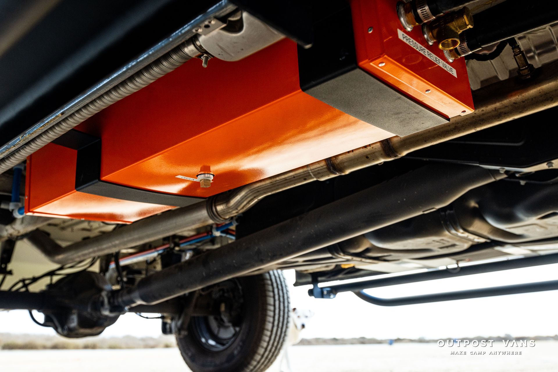 The underside of a car with a fuel tank attached to it.