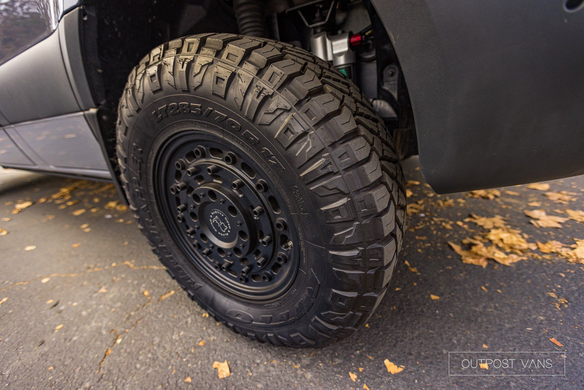 a close up of a tire on a car with leaves on the ground .