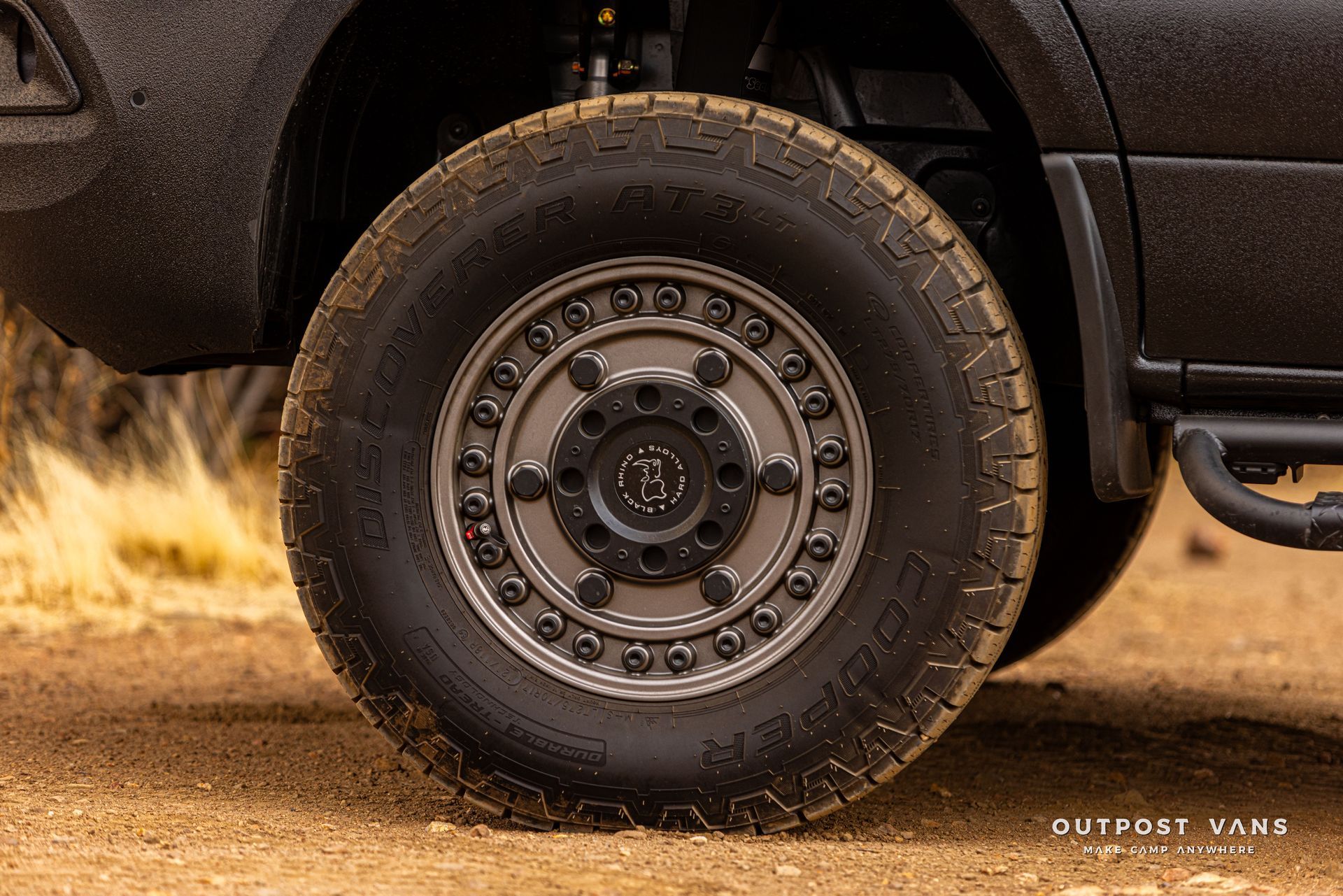 A close up of a tire on a truck on a dirt road.