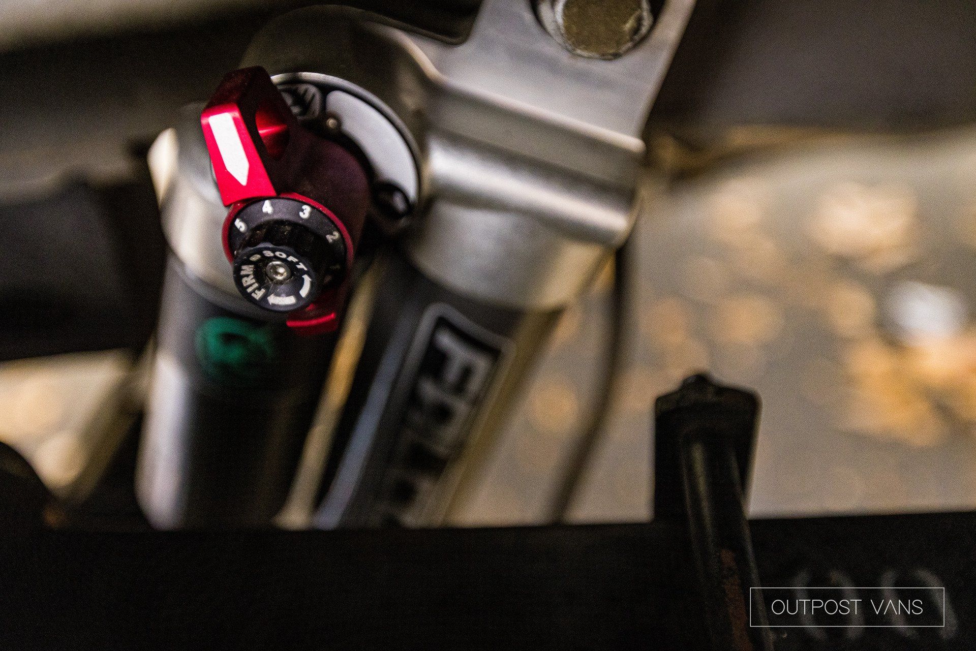 a close up of a bicycle shock with a red knob on it .