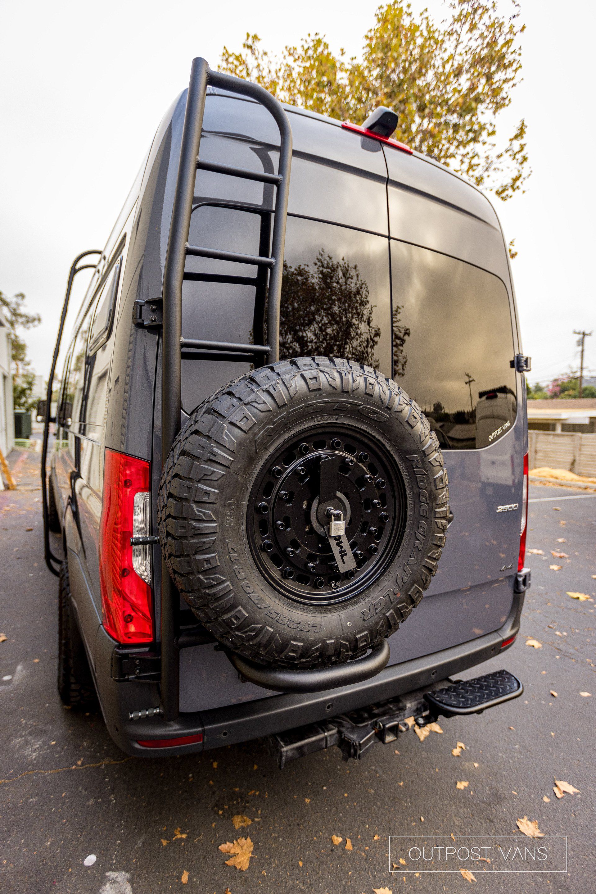 a van with a spare tire attached to the back of it is parked on the side of the road .
