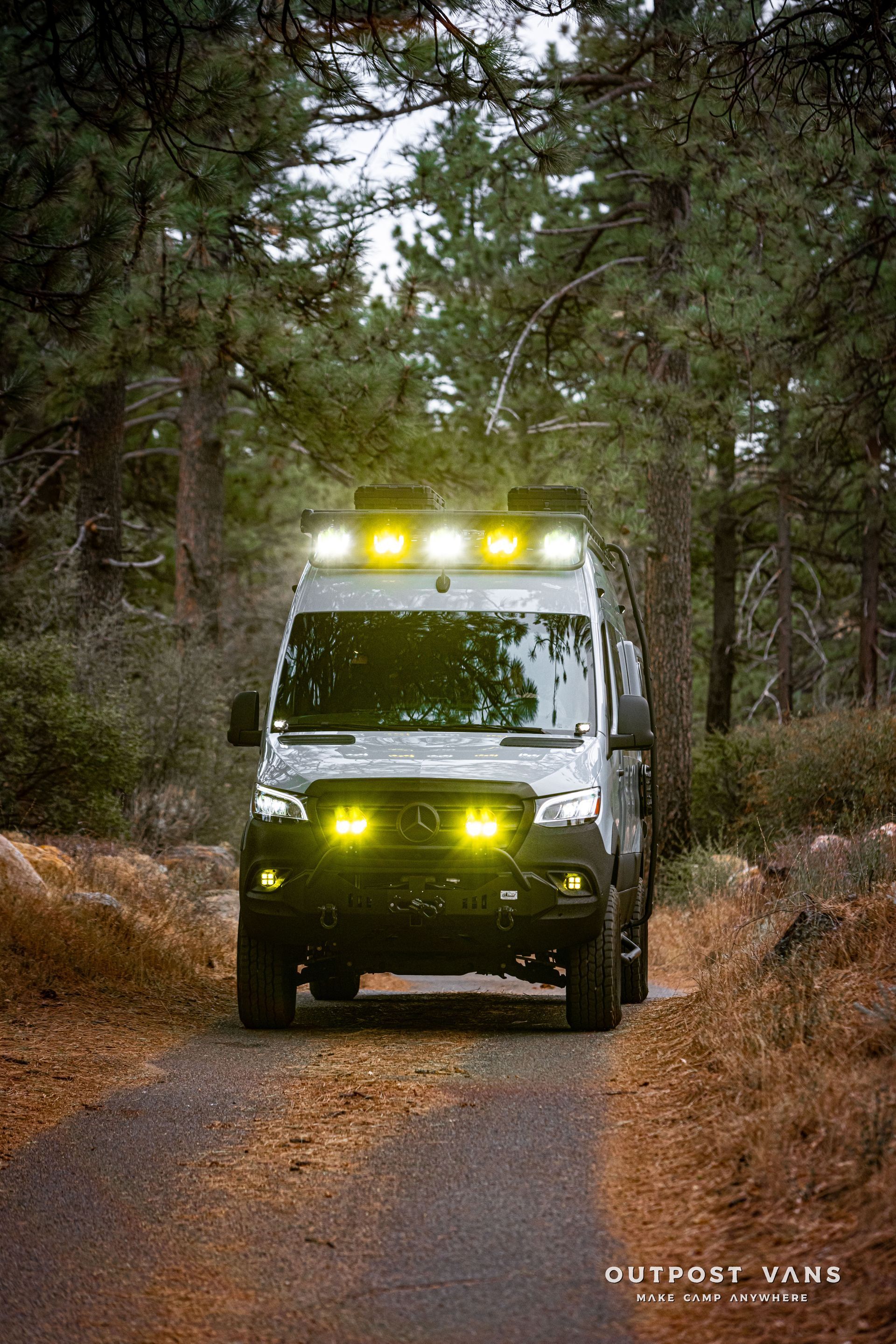 A van is driving down a dirt road in the woods.