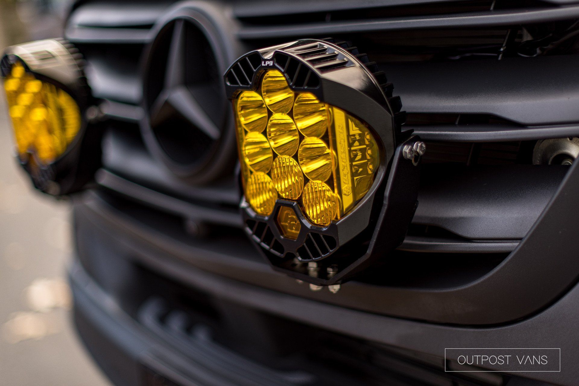 A close up of the front of a mercedes with yellow lights on it.