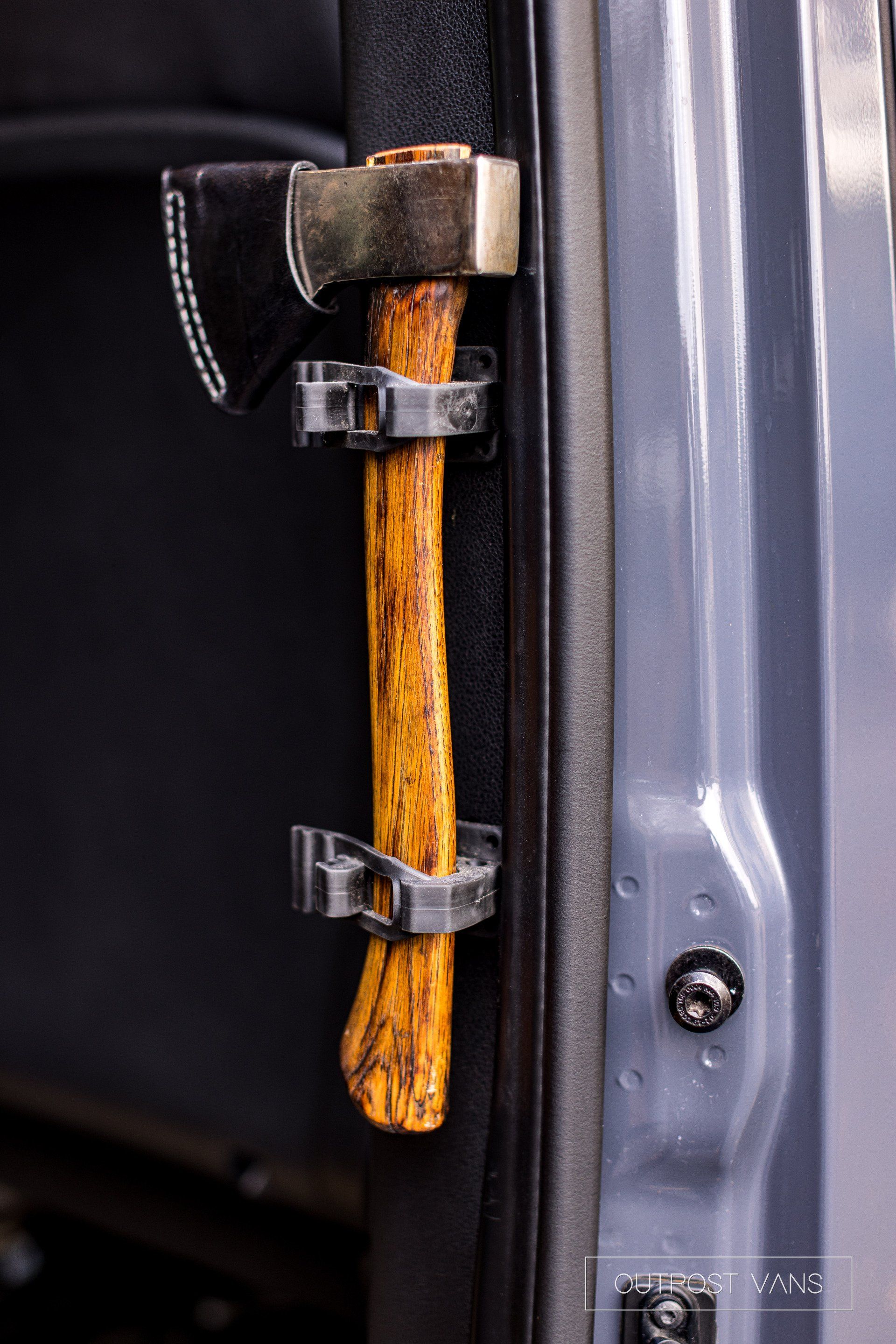 A close up of a hatchet hanging from the door of a car.