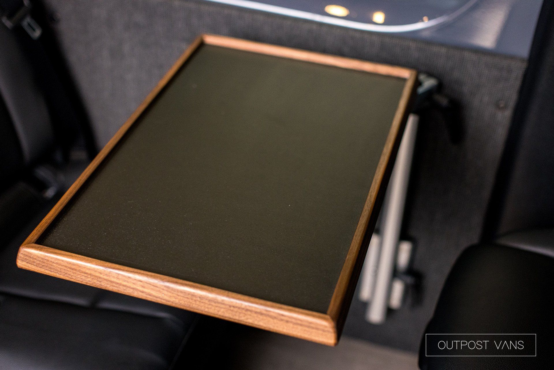 A wooden tray is attached to the back seat of a car