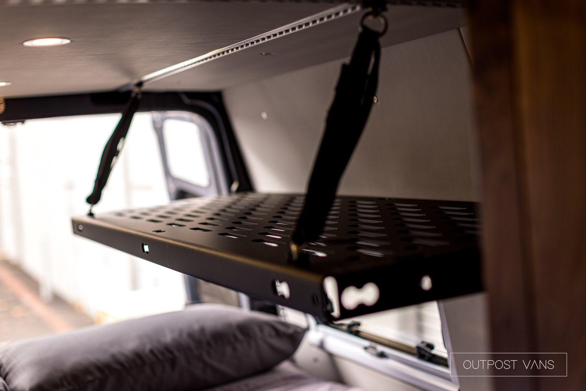 A shelf is hanging from the ceiling of a van.