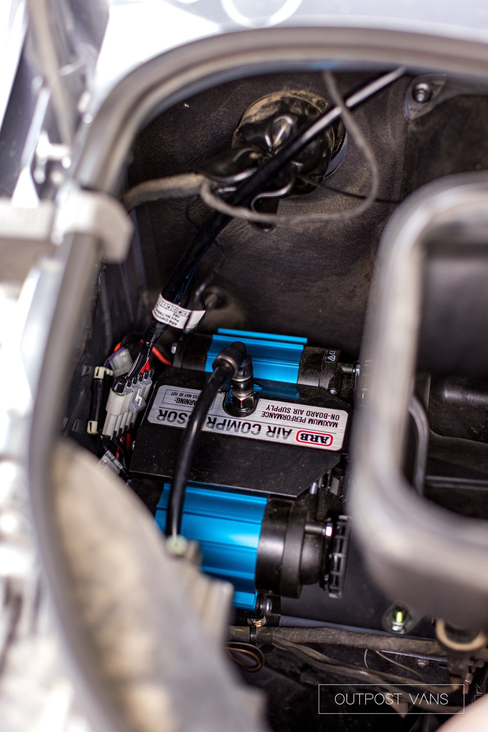 A blue air compressor is sitting inside of a car.