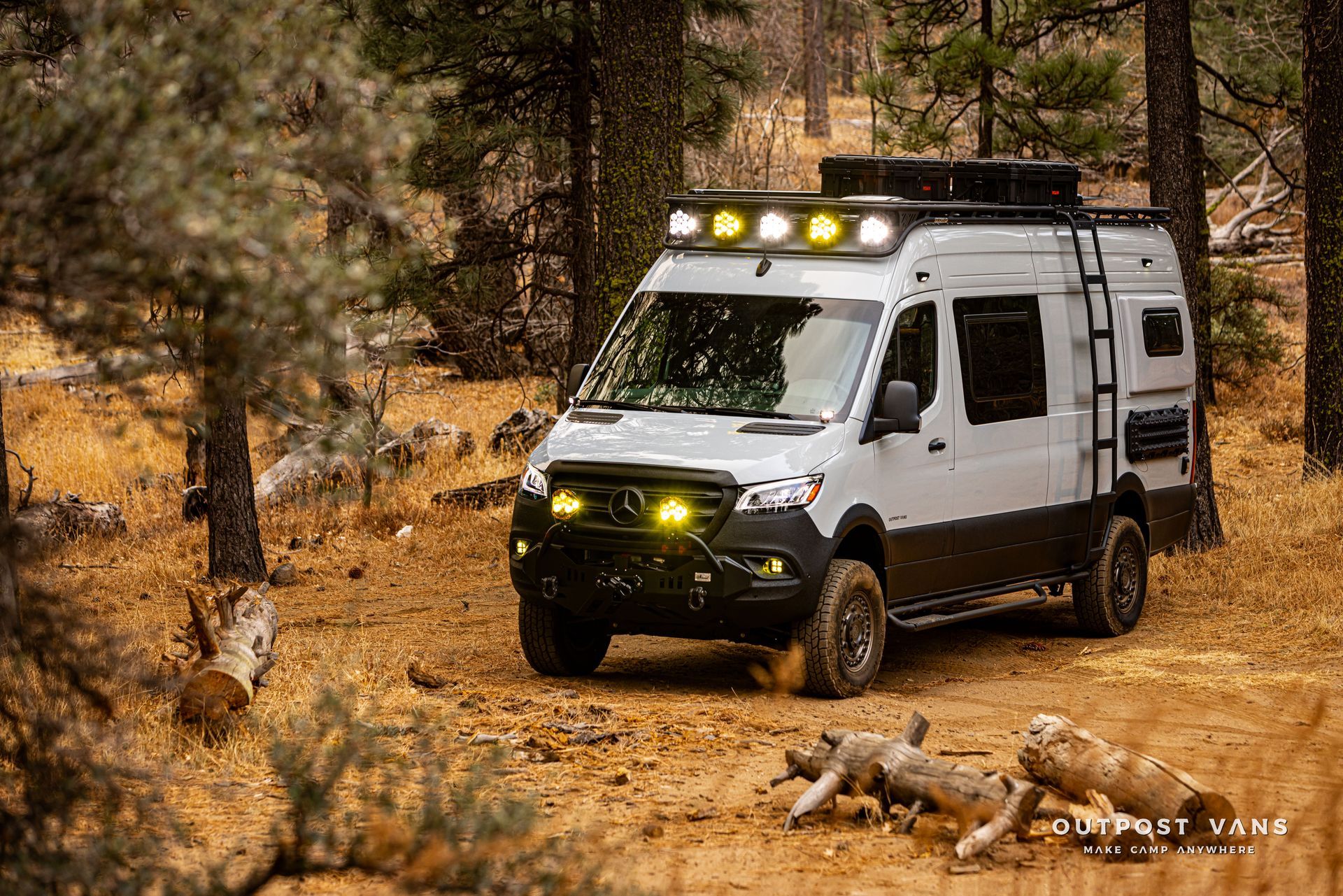 A white van is parked in the middle of a forest.
