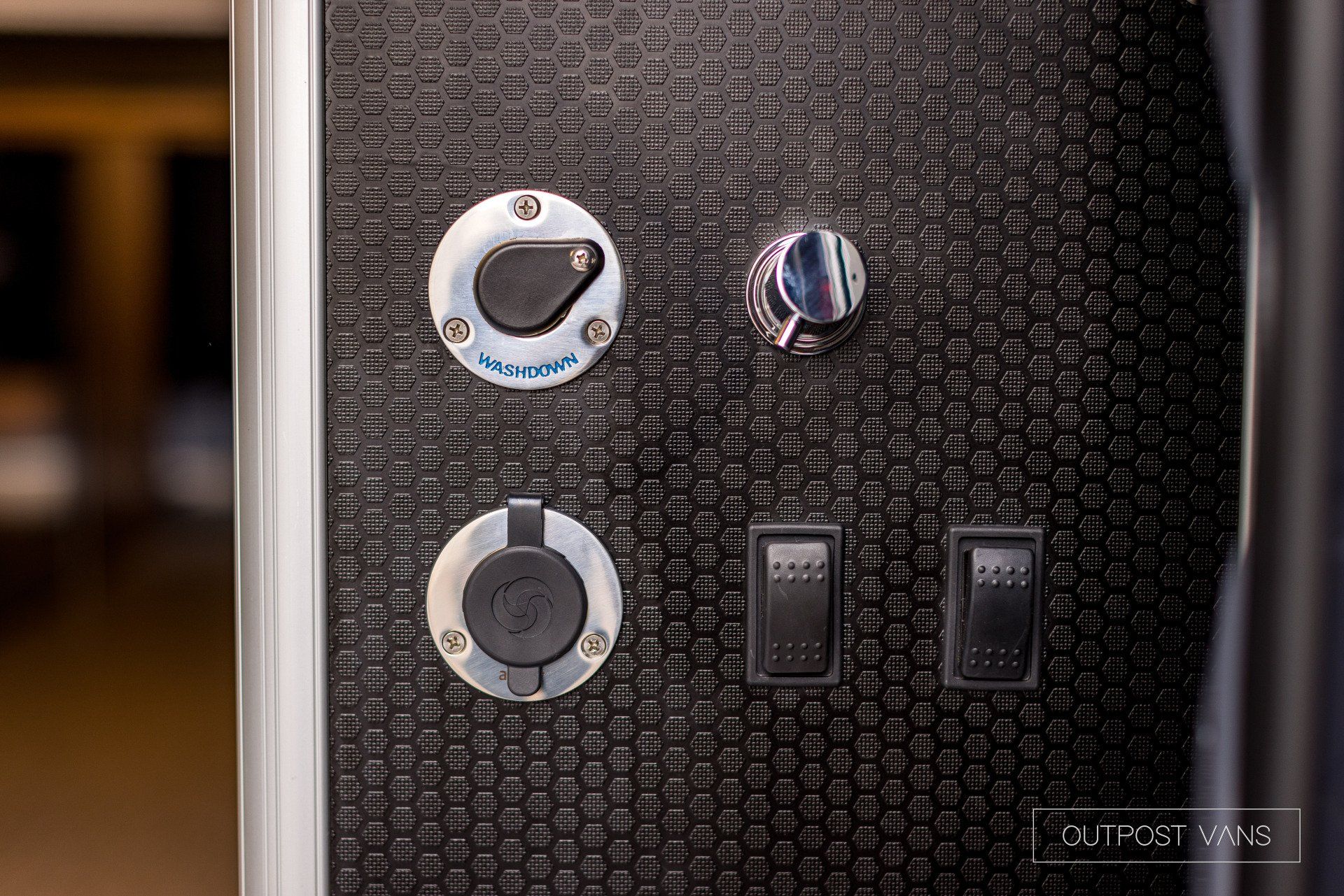 A close up of a black wall with a bunch of switches on it.