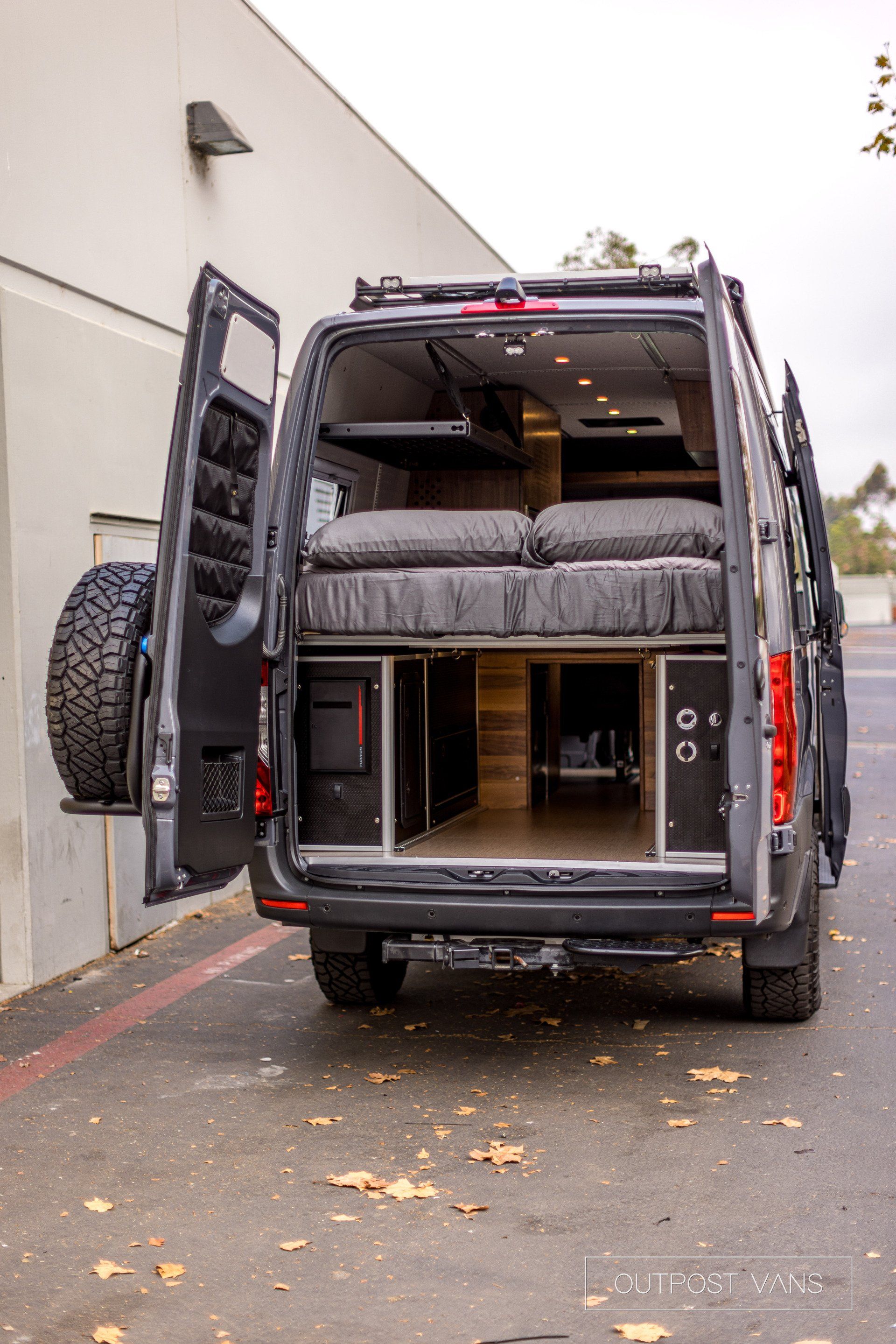 A van with the back door open is parked in a parking lot.