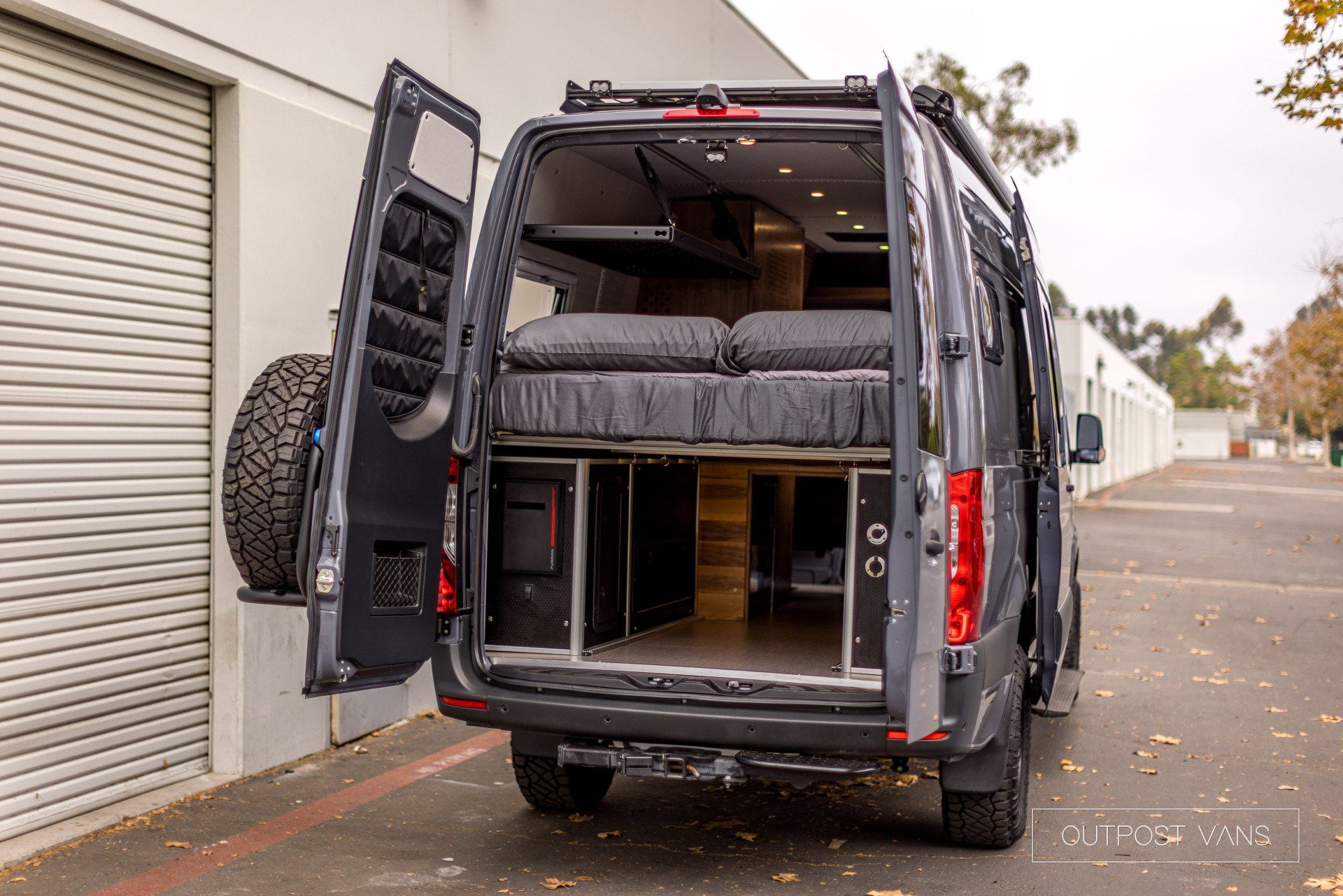 A van with the back door open is parked in a parking lot.