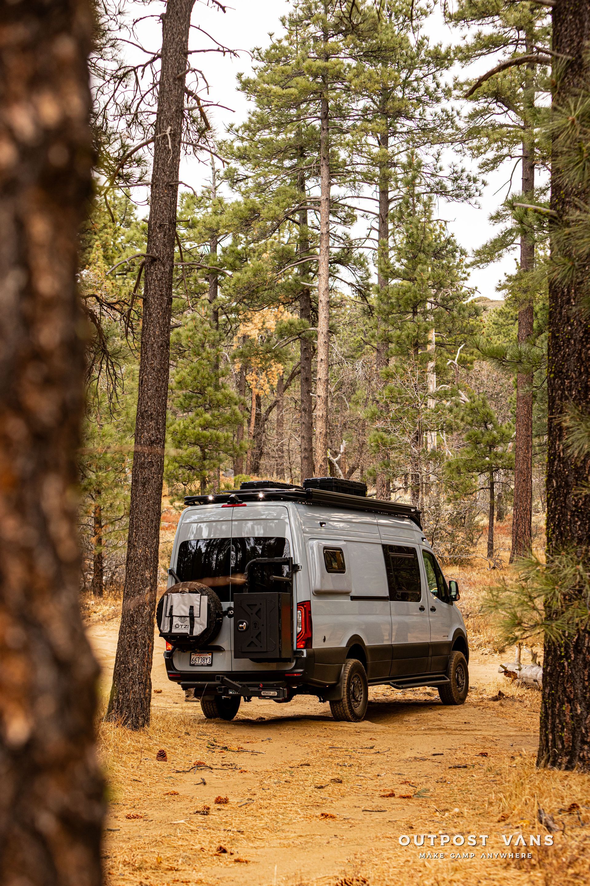 A van is parked in the middle of a forest.