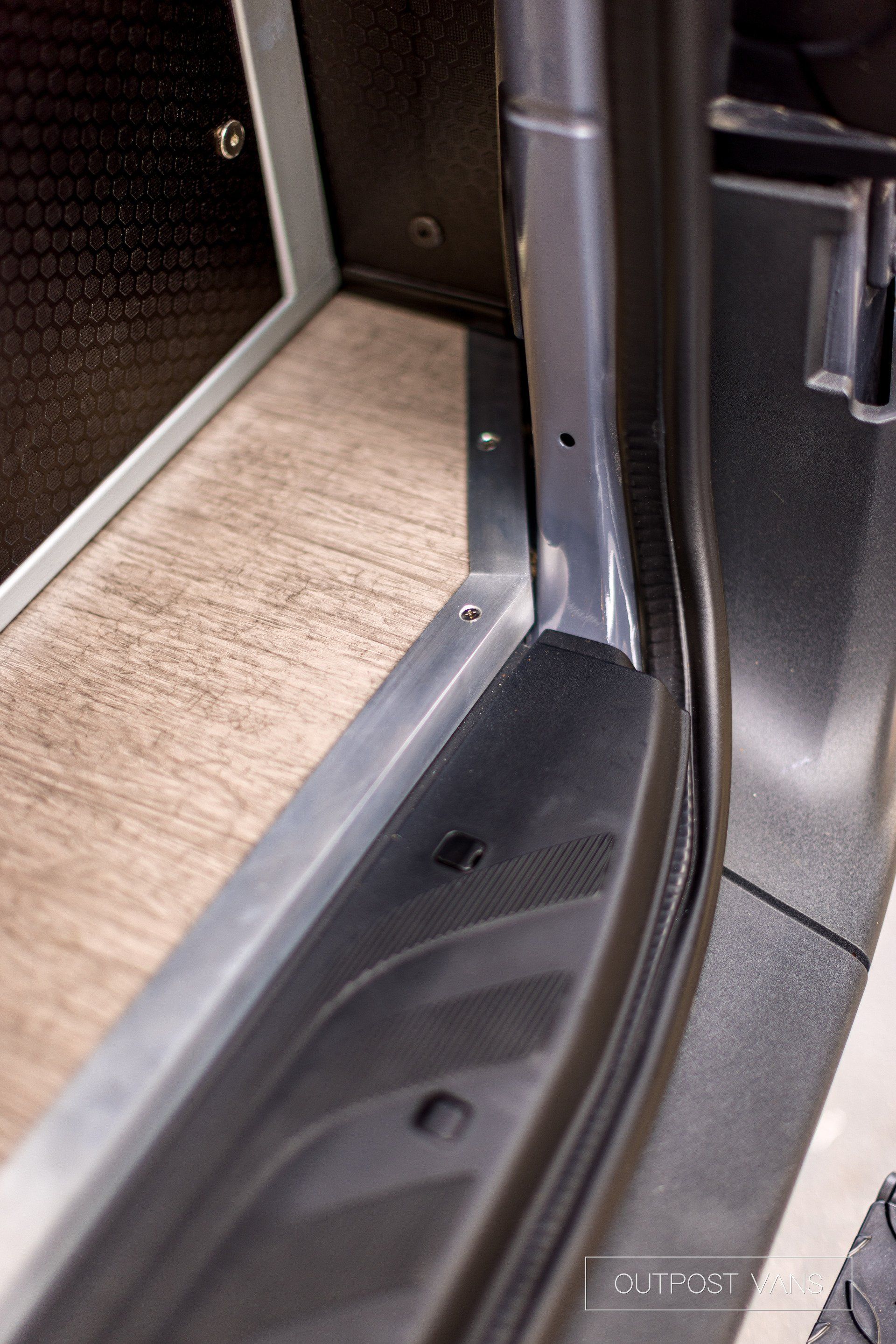 A close up of a car door with a wooden floor