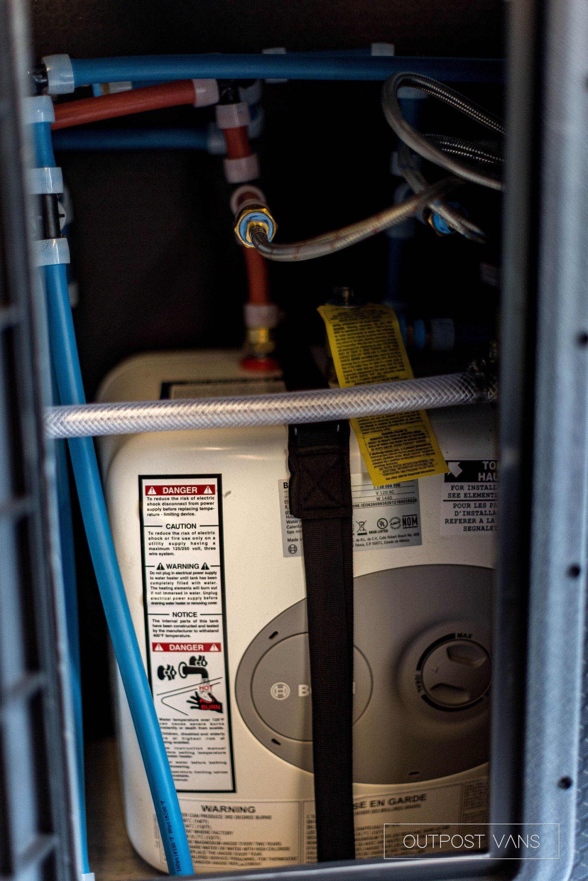 A water heater is sitting inside of a cage.