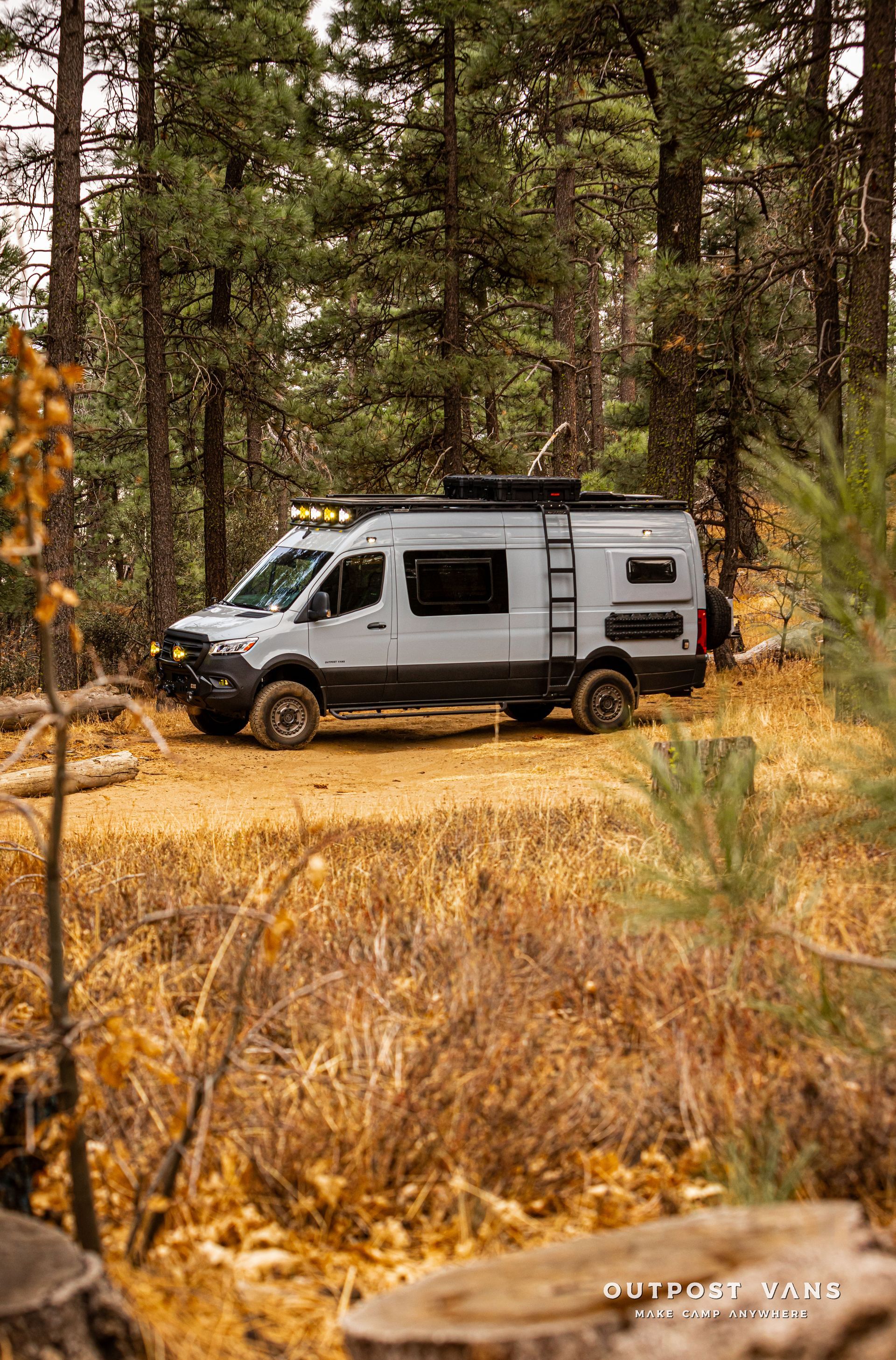 A van is parked in the middle of a forest.