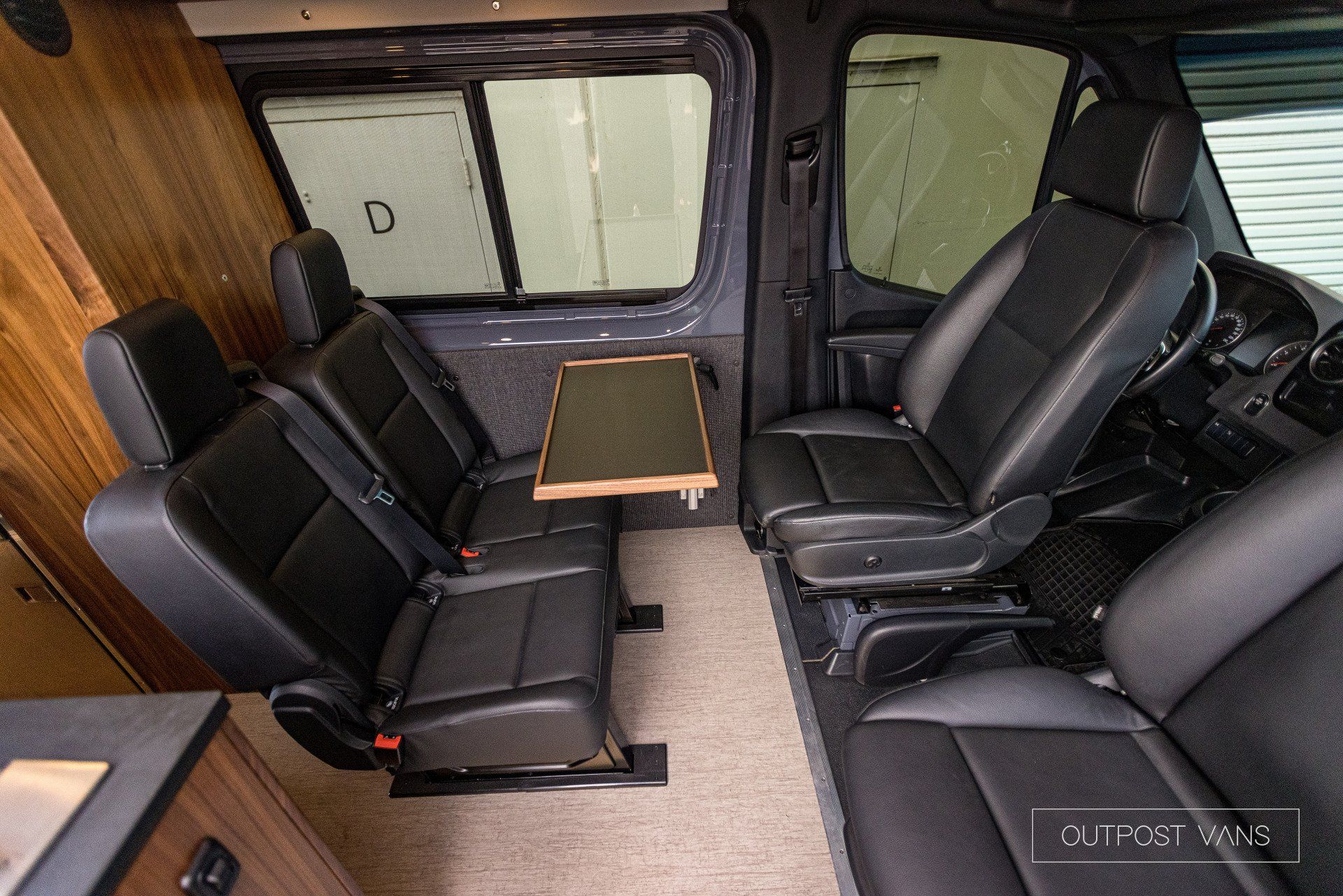 The inside of a van with leather seats and a table.