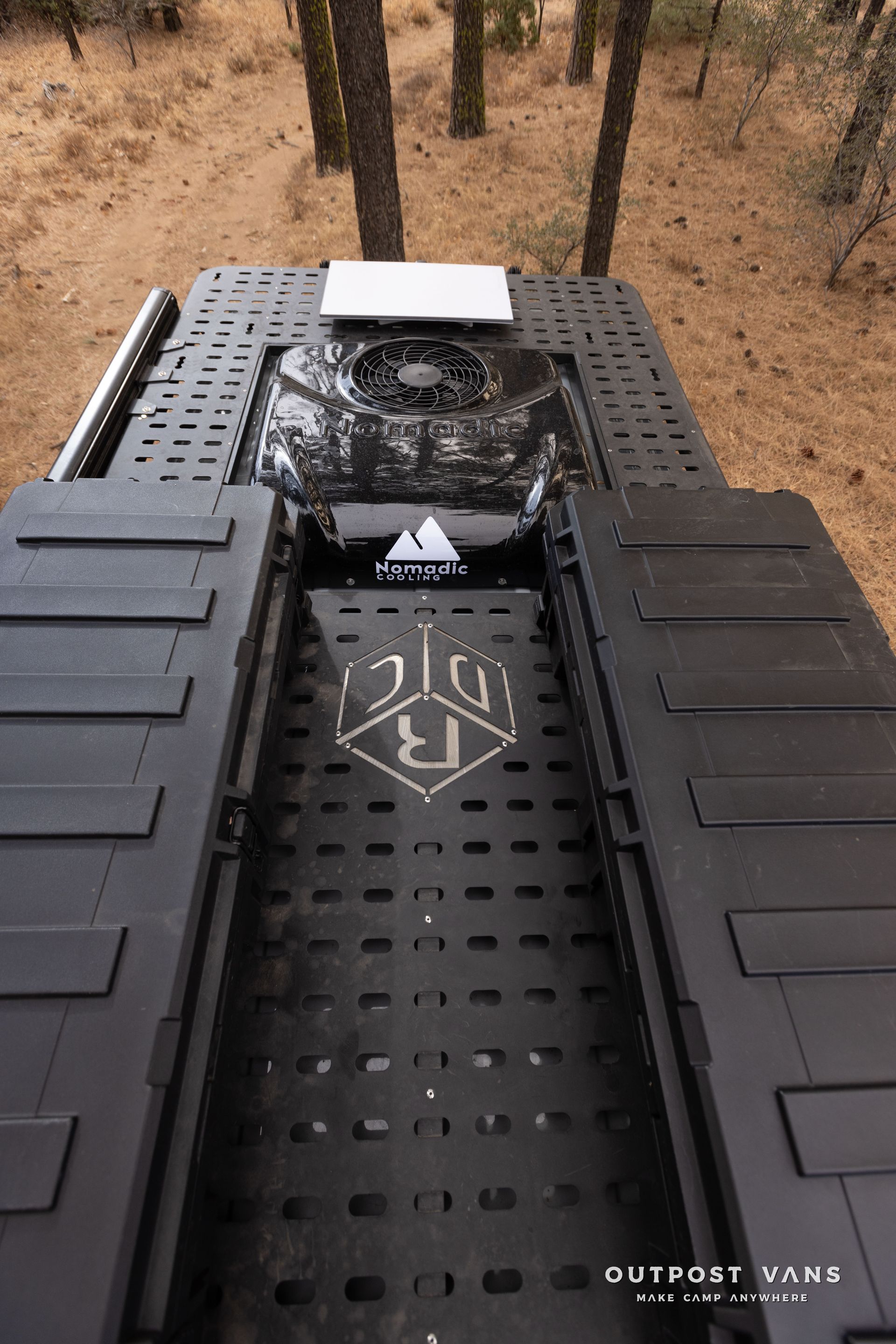A black vehicle is parked in the middle of a forest.