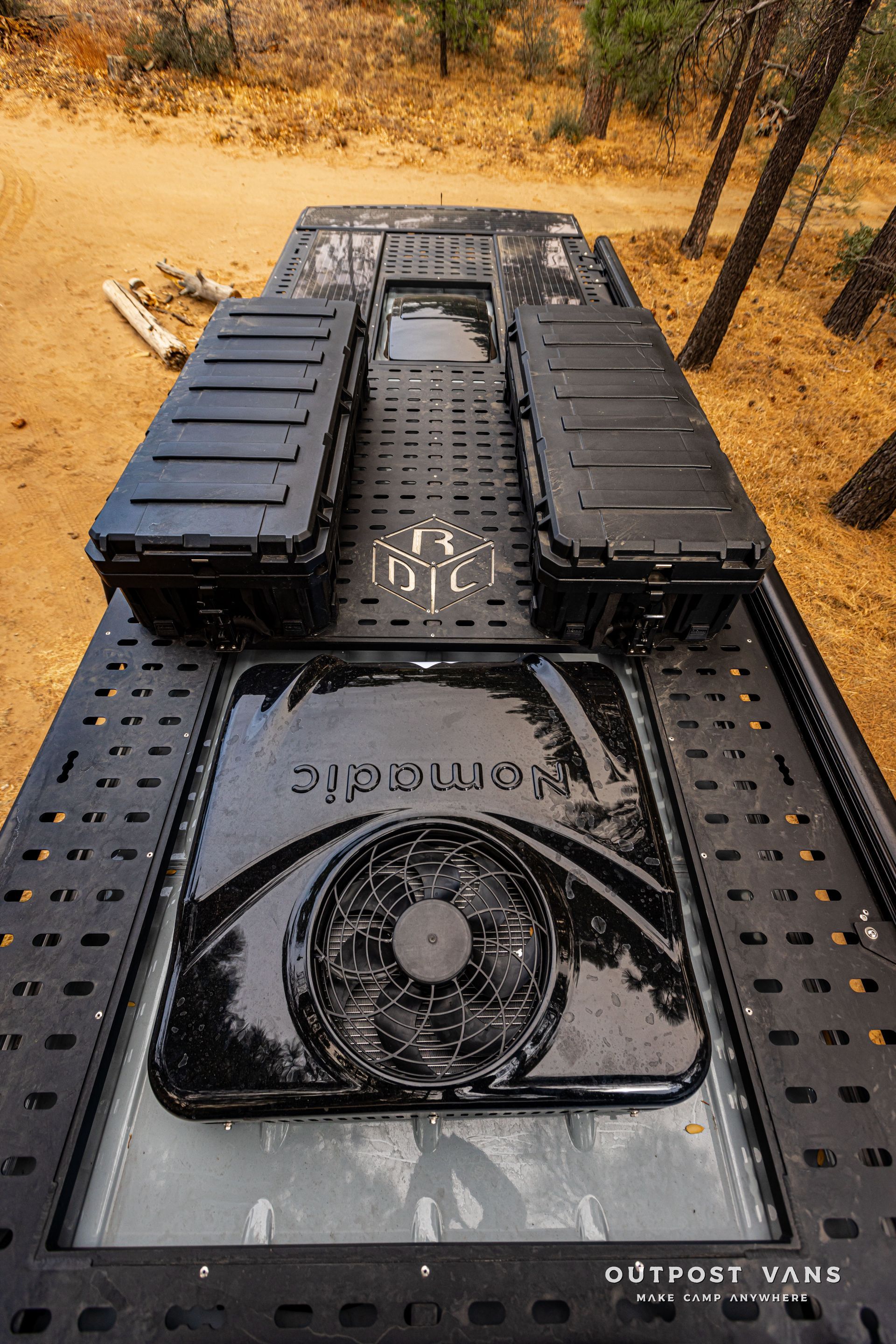 The bottom of a truck with a fan on it is sitting on top of a dirt road.