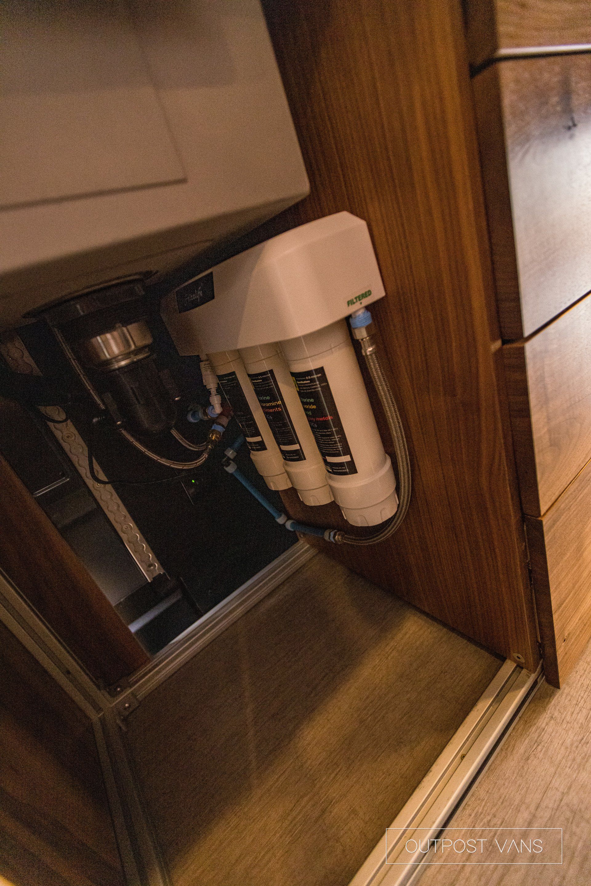 A water filter is installed under a sink in a kitchen.
