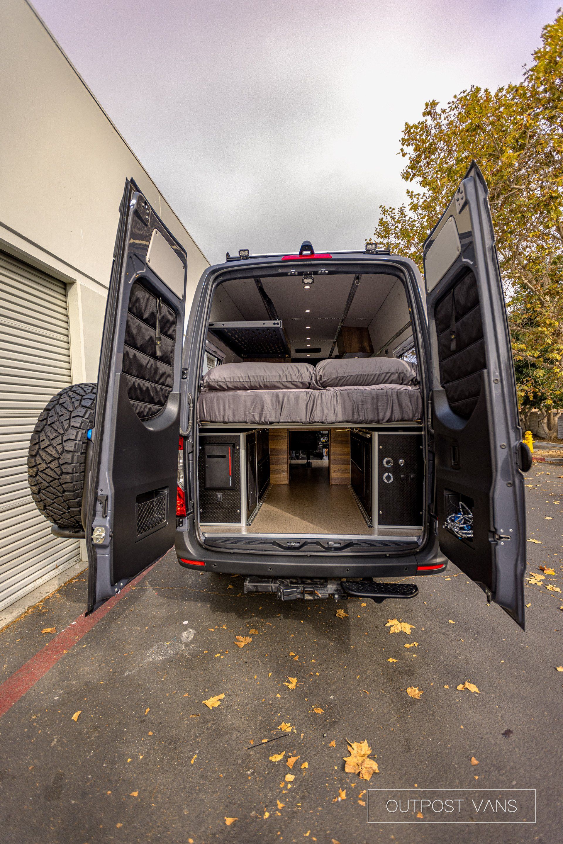 A van with its doors open is parked in front of a building.