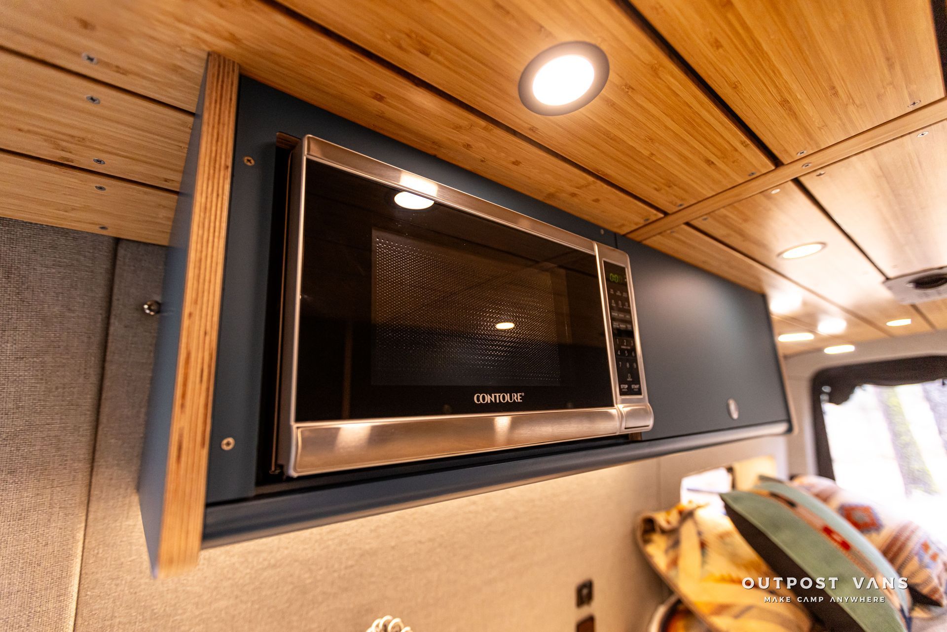 A microwave oven is mounted on the wall of a camper van.