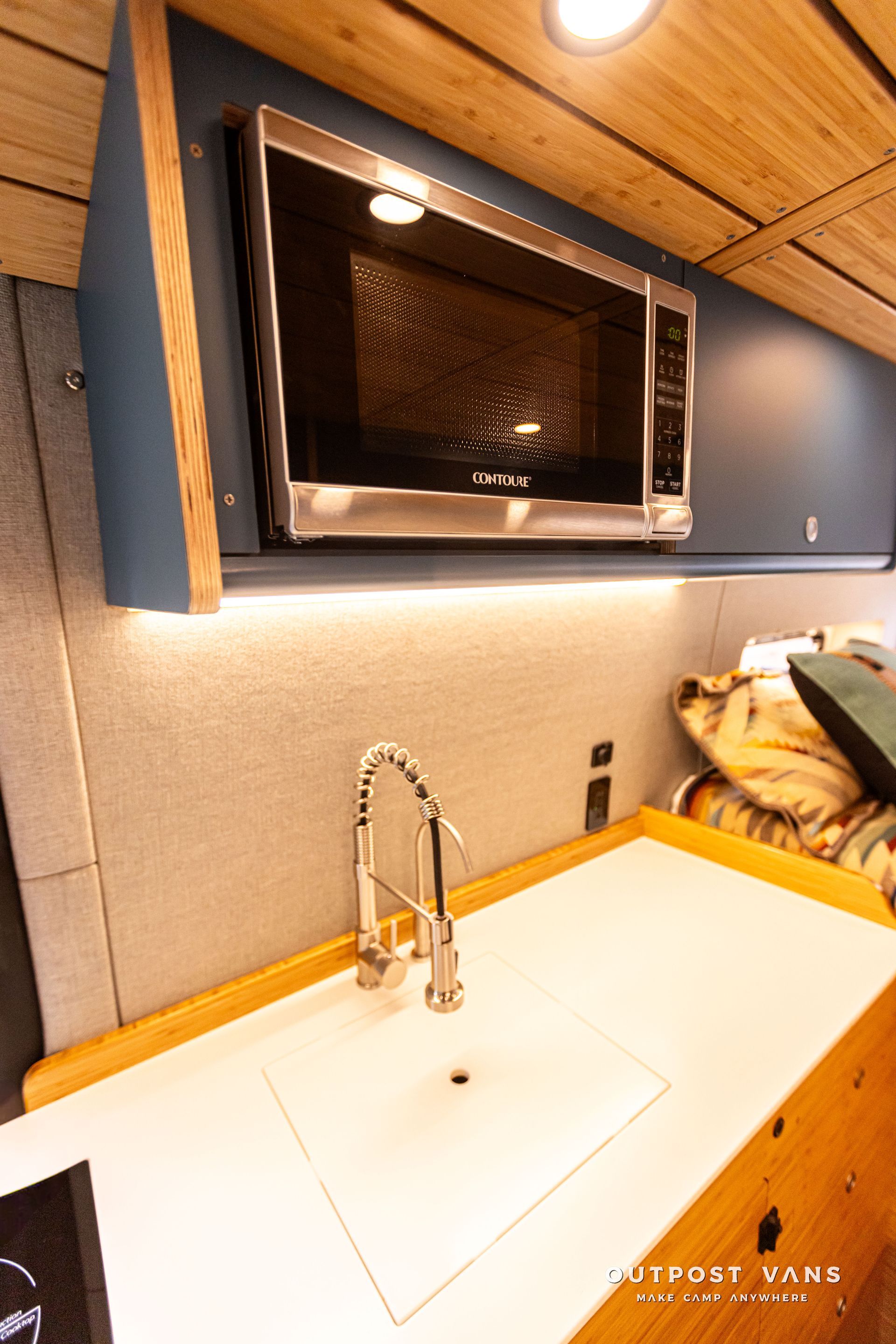 A kitchen with a sink , microwave , and faucet.