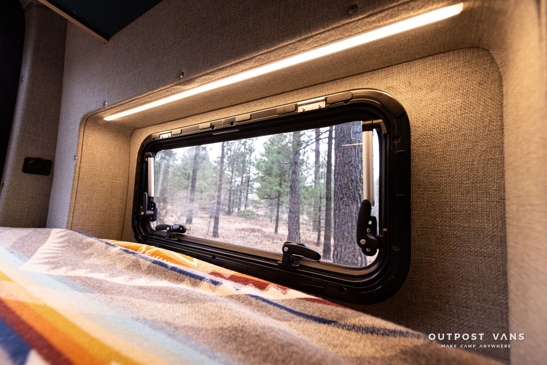 FLARESPACE bed with a blanket on it and a TERN OVERLAND window with a forest view.