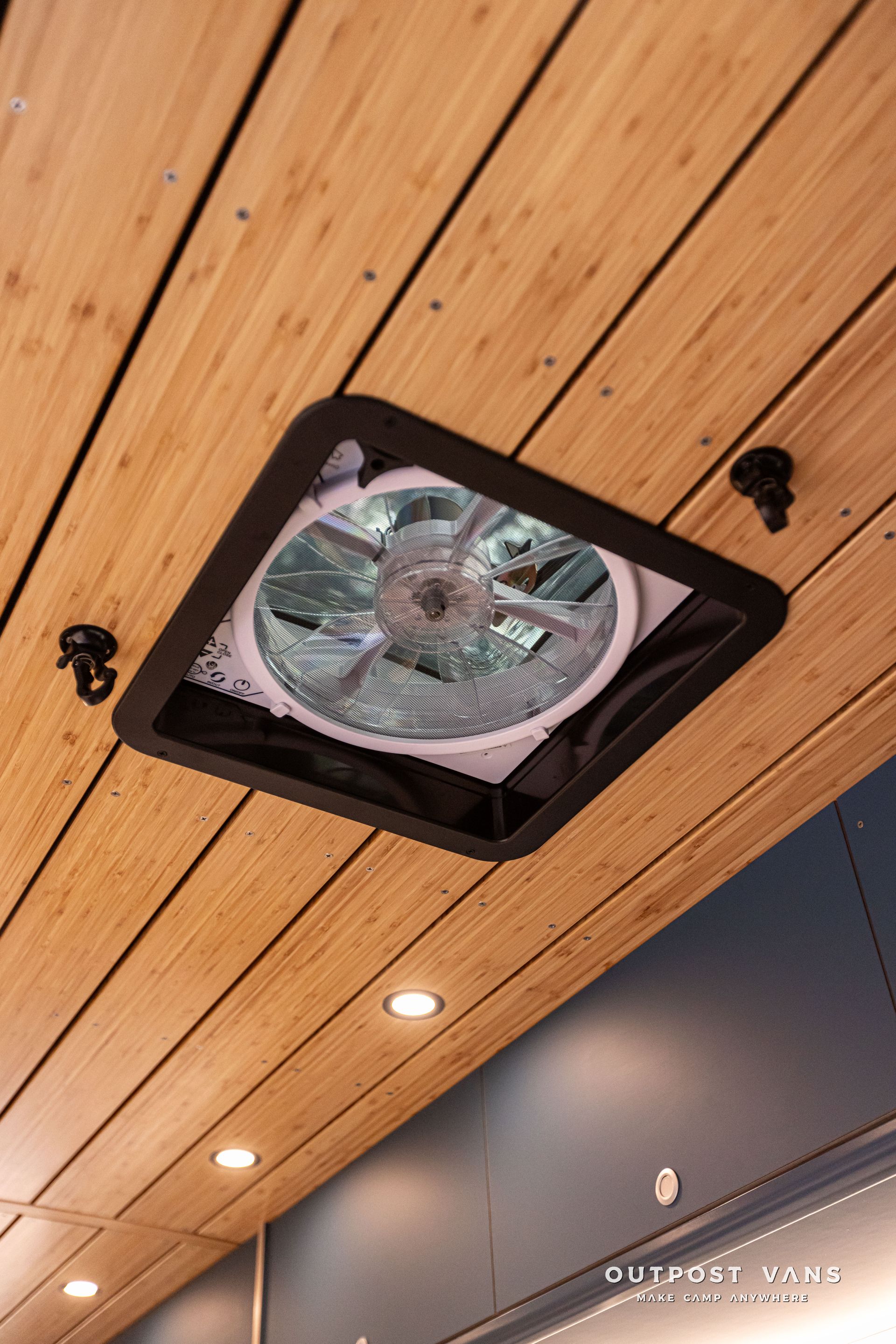 A fan is hanging from the ceiling of a wooden room.