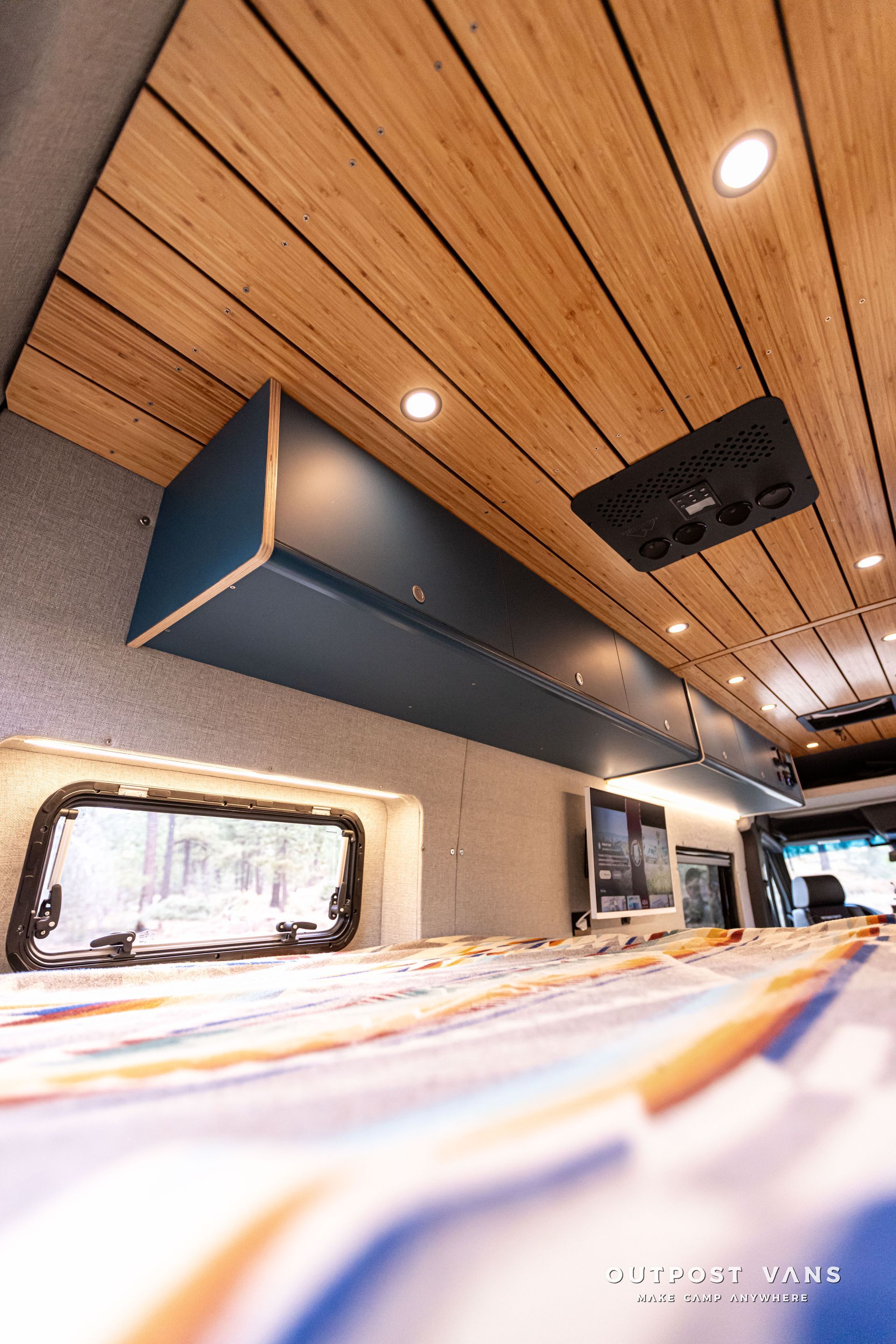 A camper van with a wooden ceiling and a bed.
