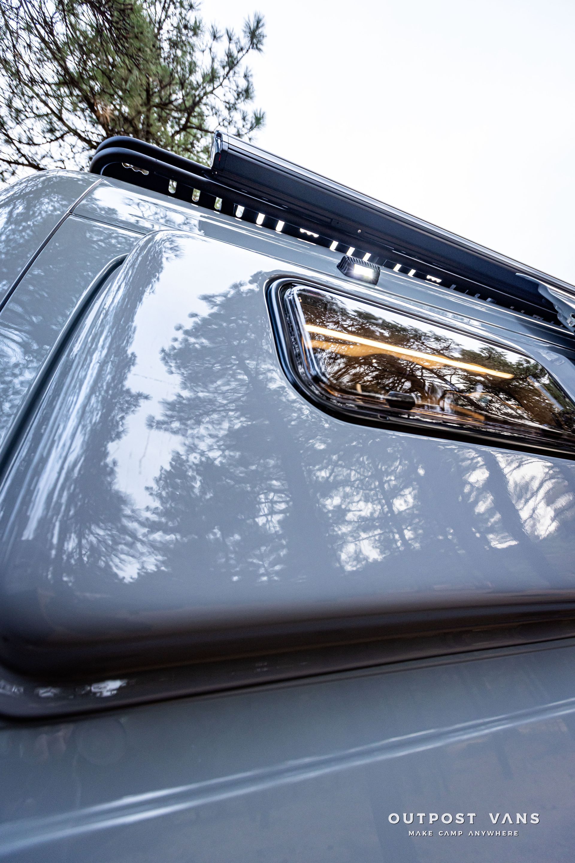 A close up of the roof of a car with trees in the background.