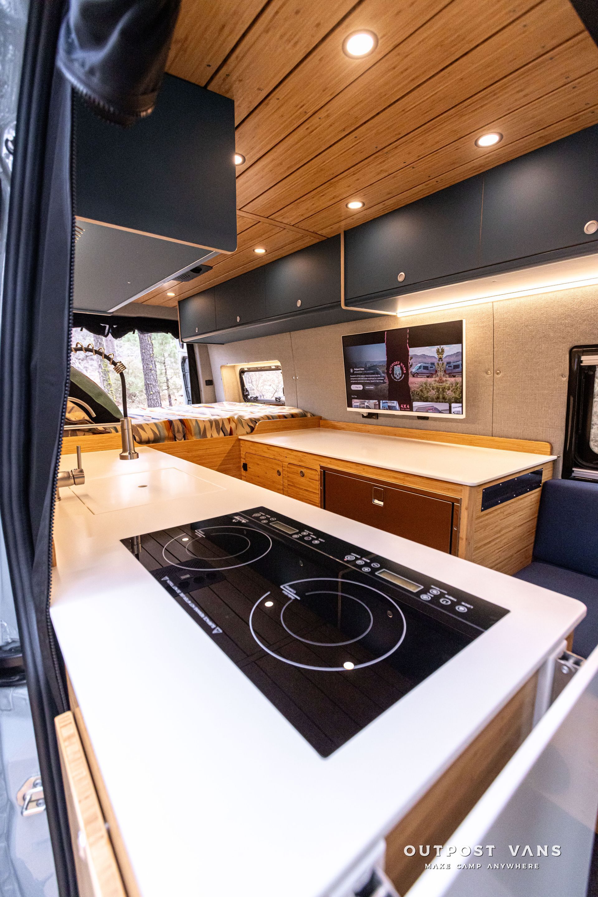 A kitchen in a van with a stove top oven and a sink.