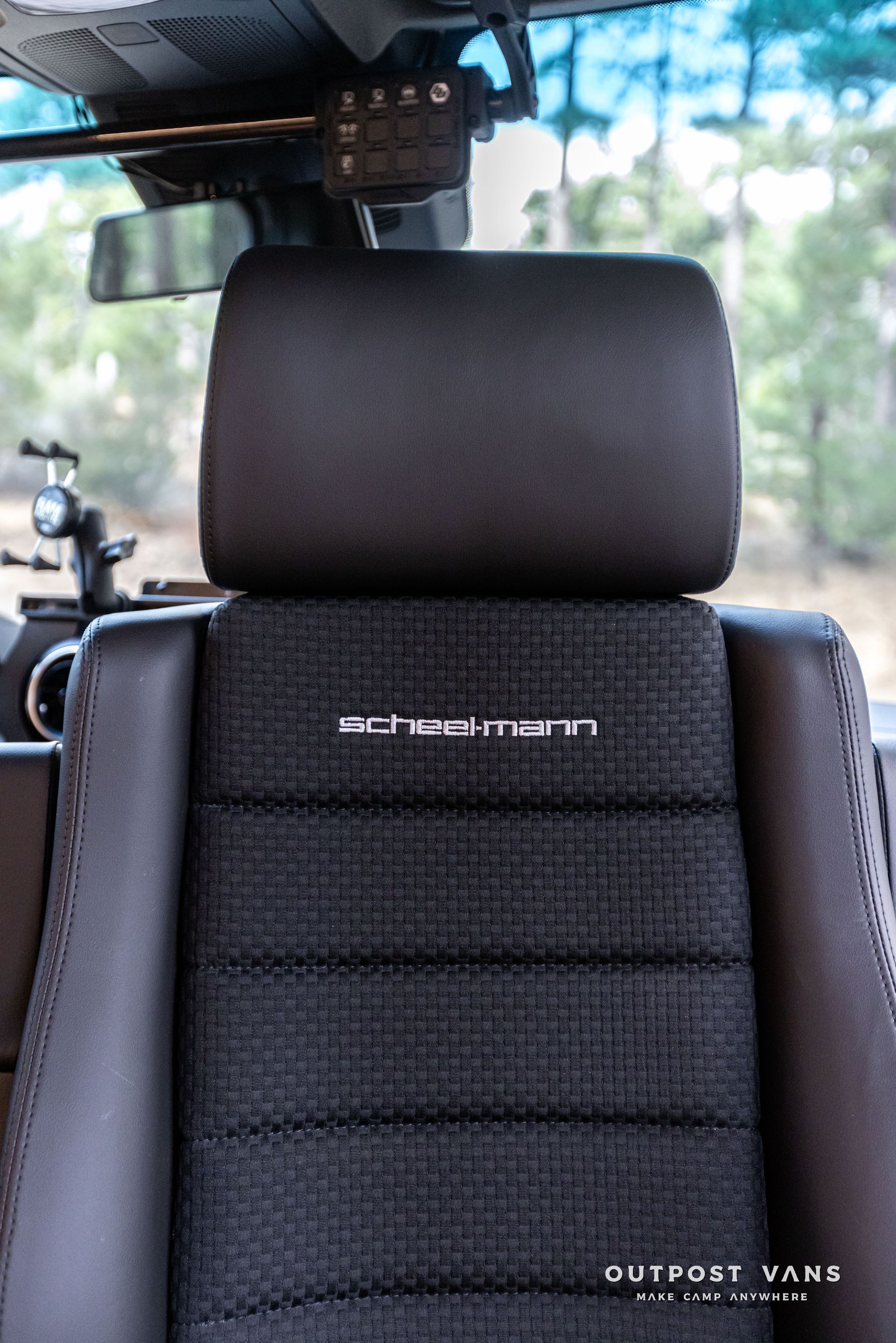 A close up of a car seat with a headrest and a rear view mirror.