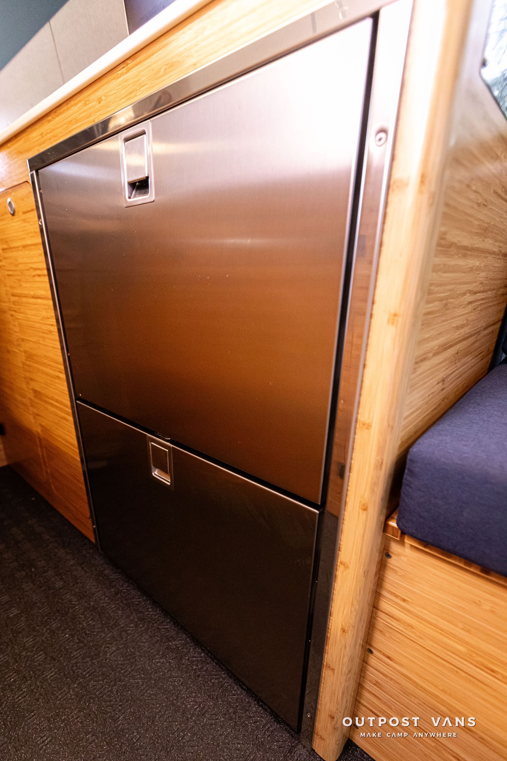 A stainless steel refrigerator is built into a wooden cabinet.