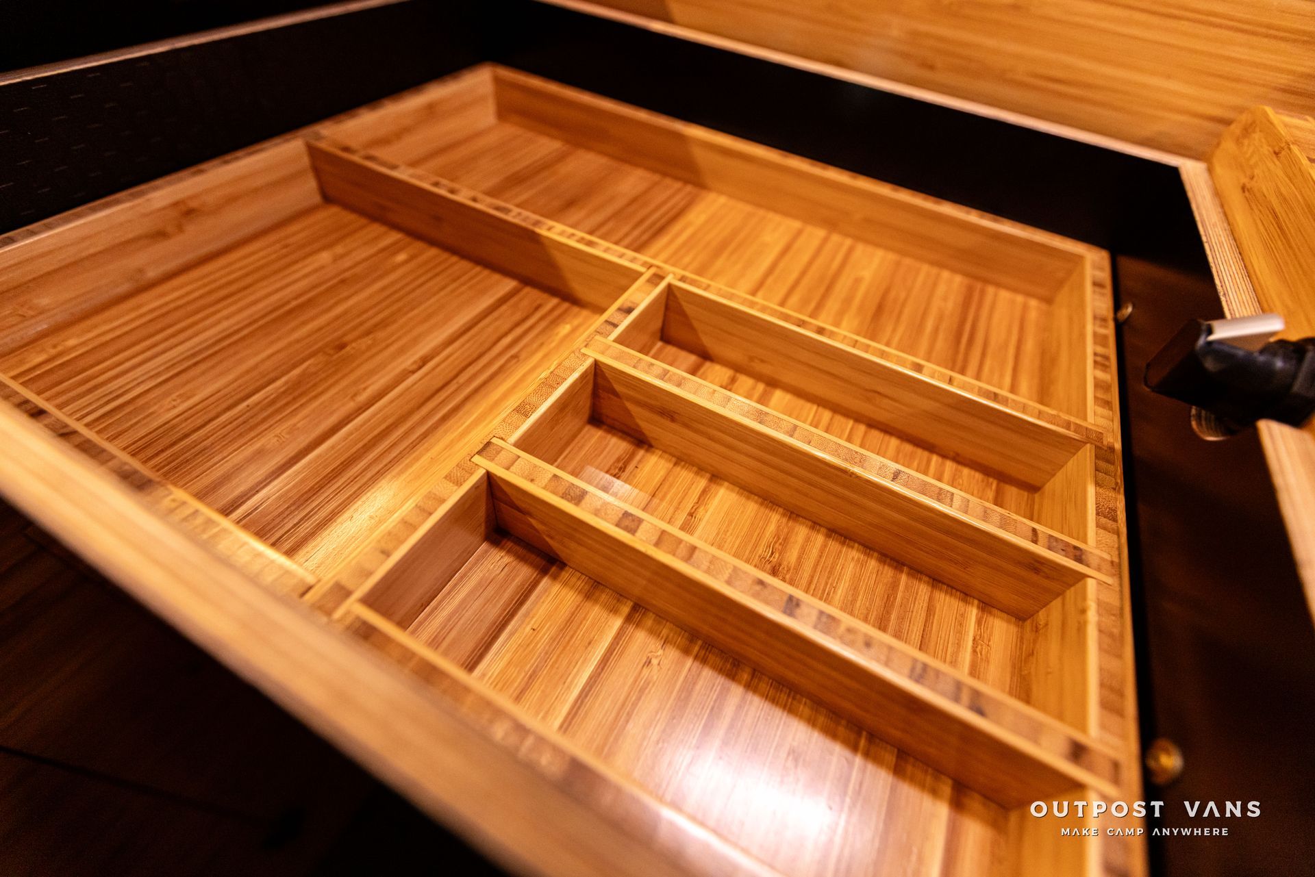 A wooden cutlery tray is sitting in a drawer.