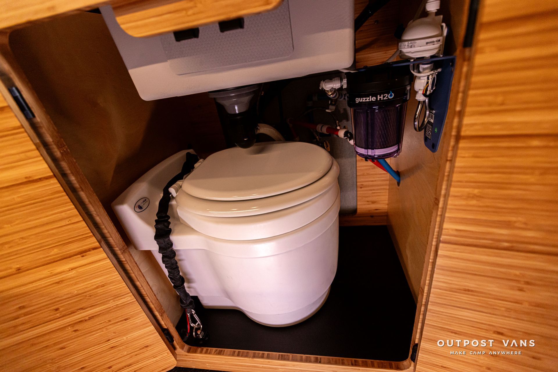 A white toilet is sitting under a wooden cabinet.