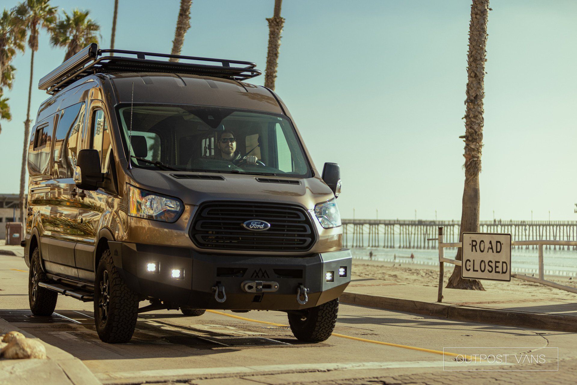 a van is parked on the side of the road next to a beach .