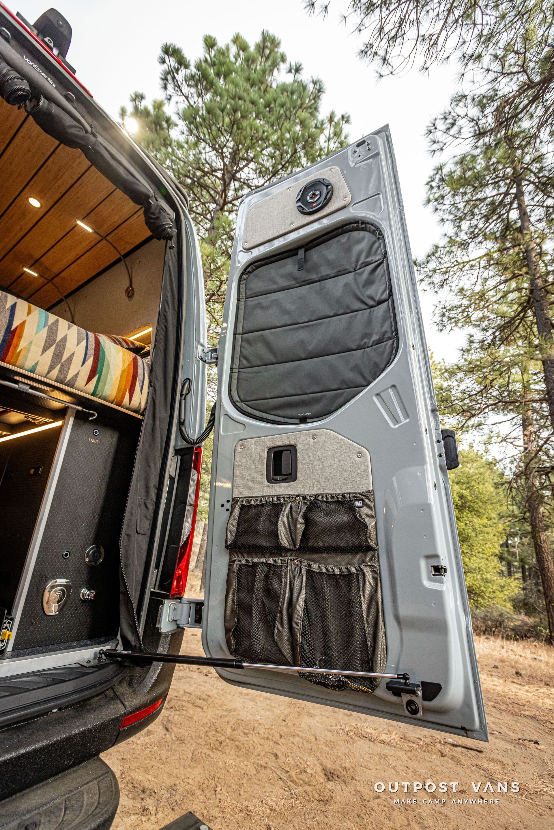 A van with its door open is parked in the woods.