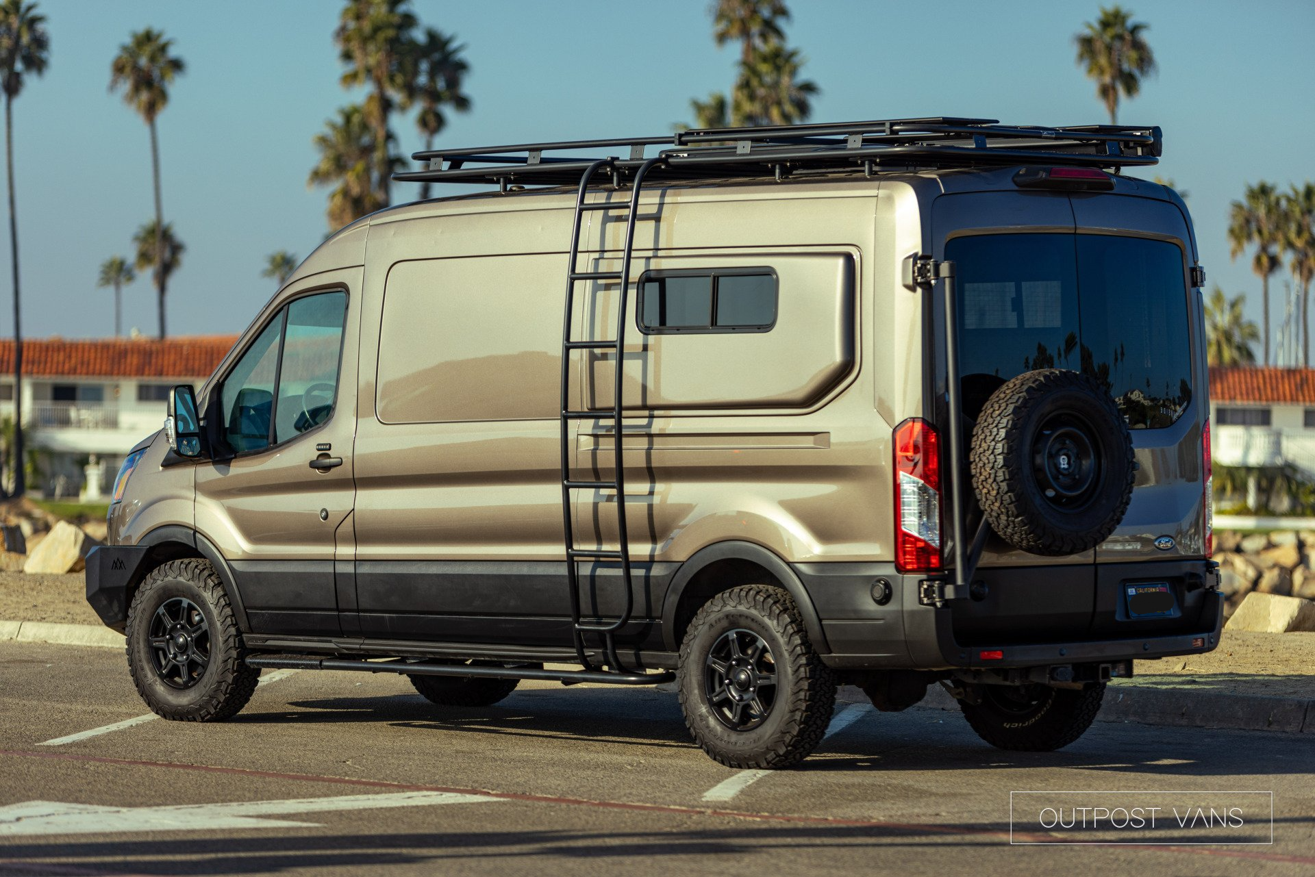 a van with a ladder on top of it is parked in a parking lot .