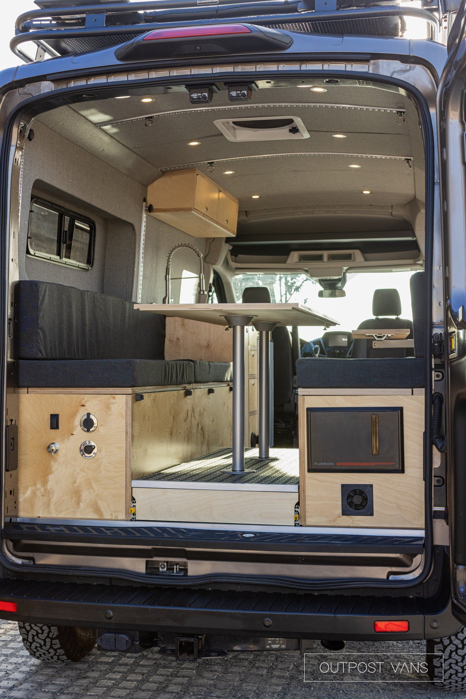 the back of a van with the door open and a table in the back .