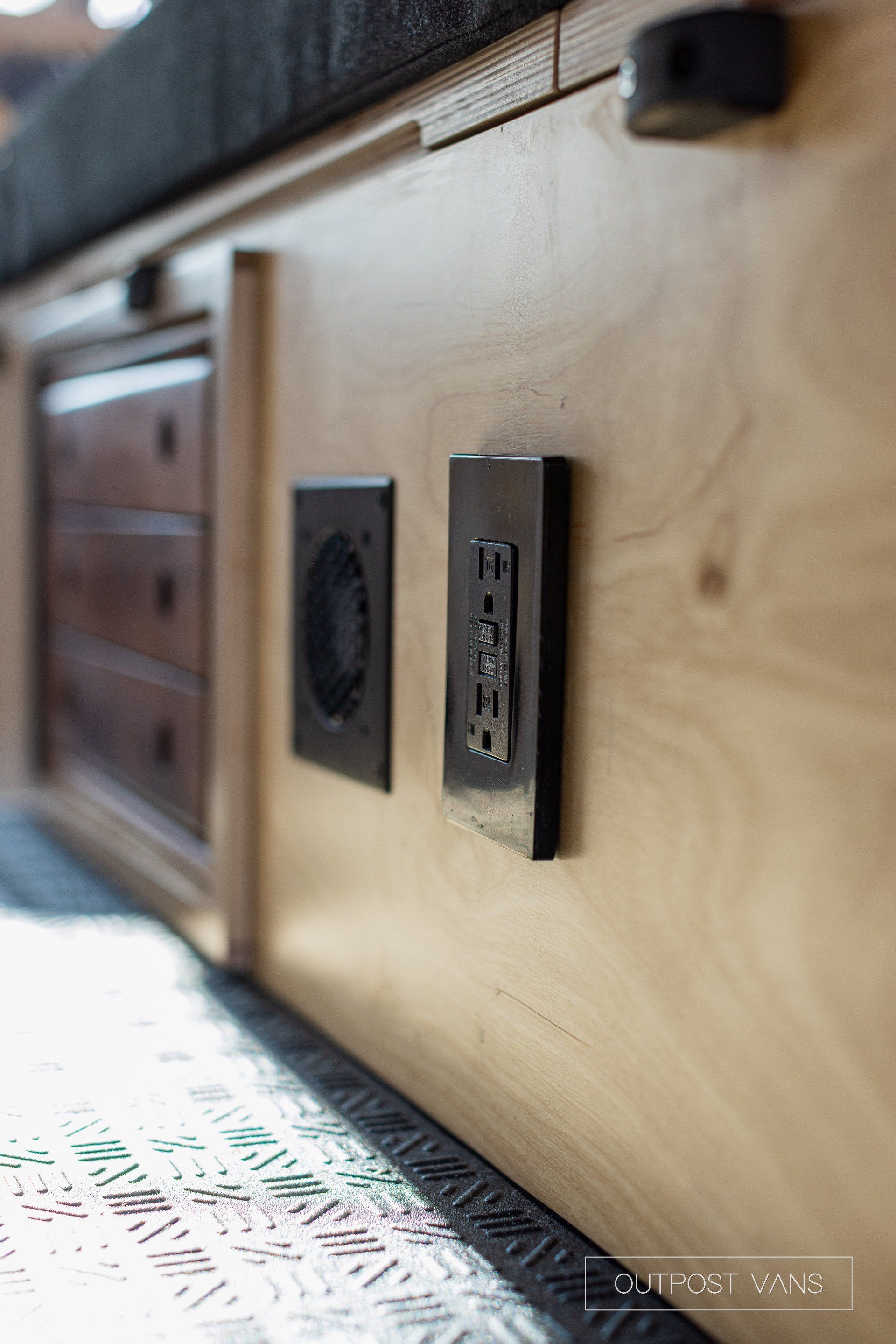 a close up of a wooden cabinet with two electrical outlets on it .