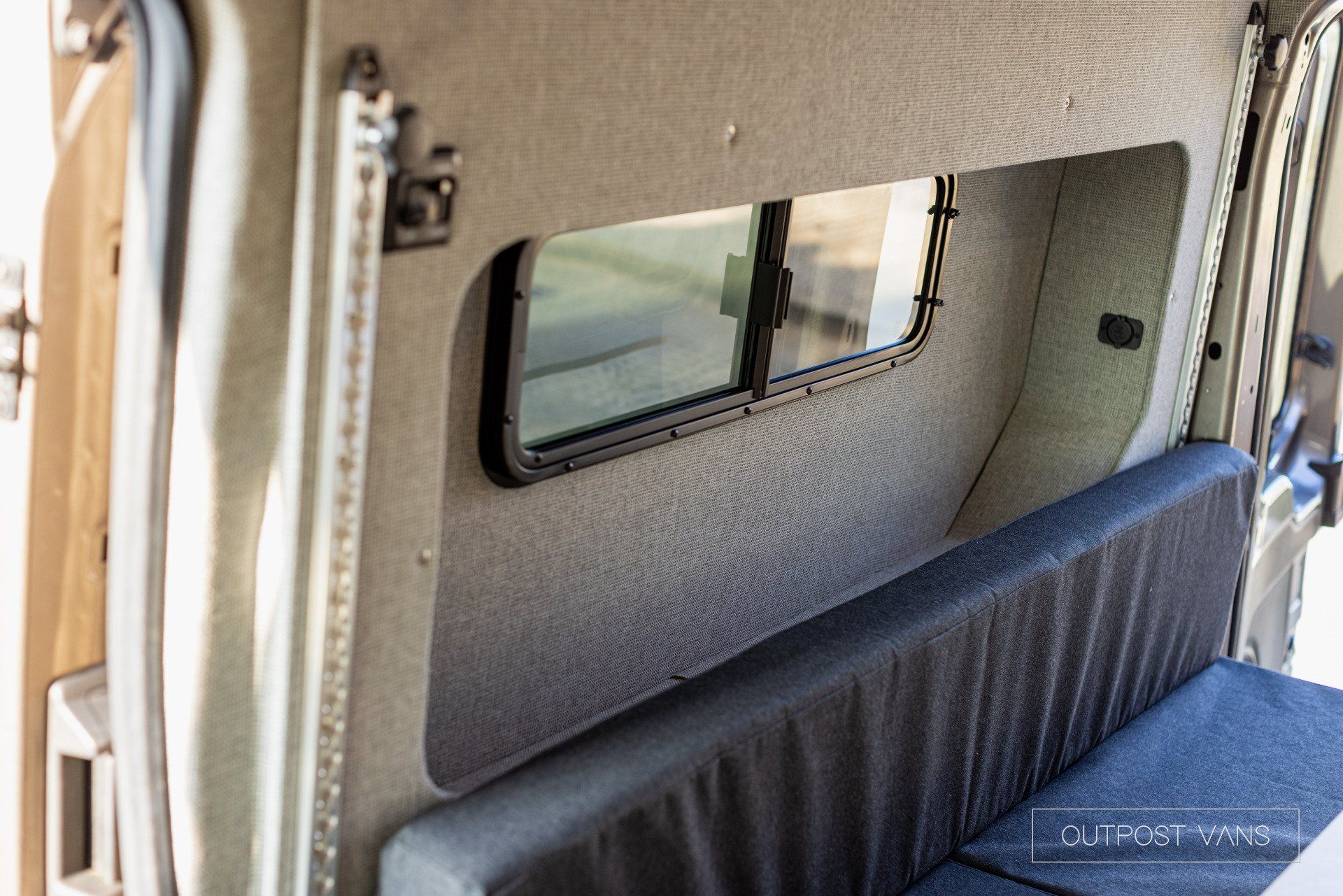the back of a van with a window and a bench .