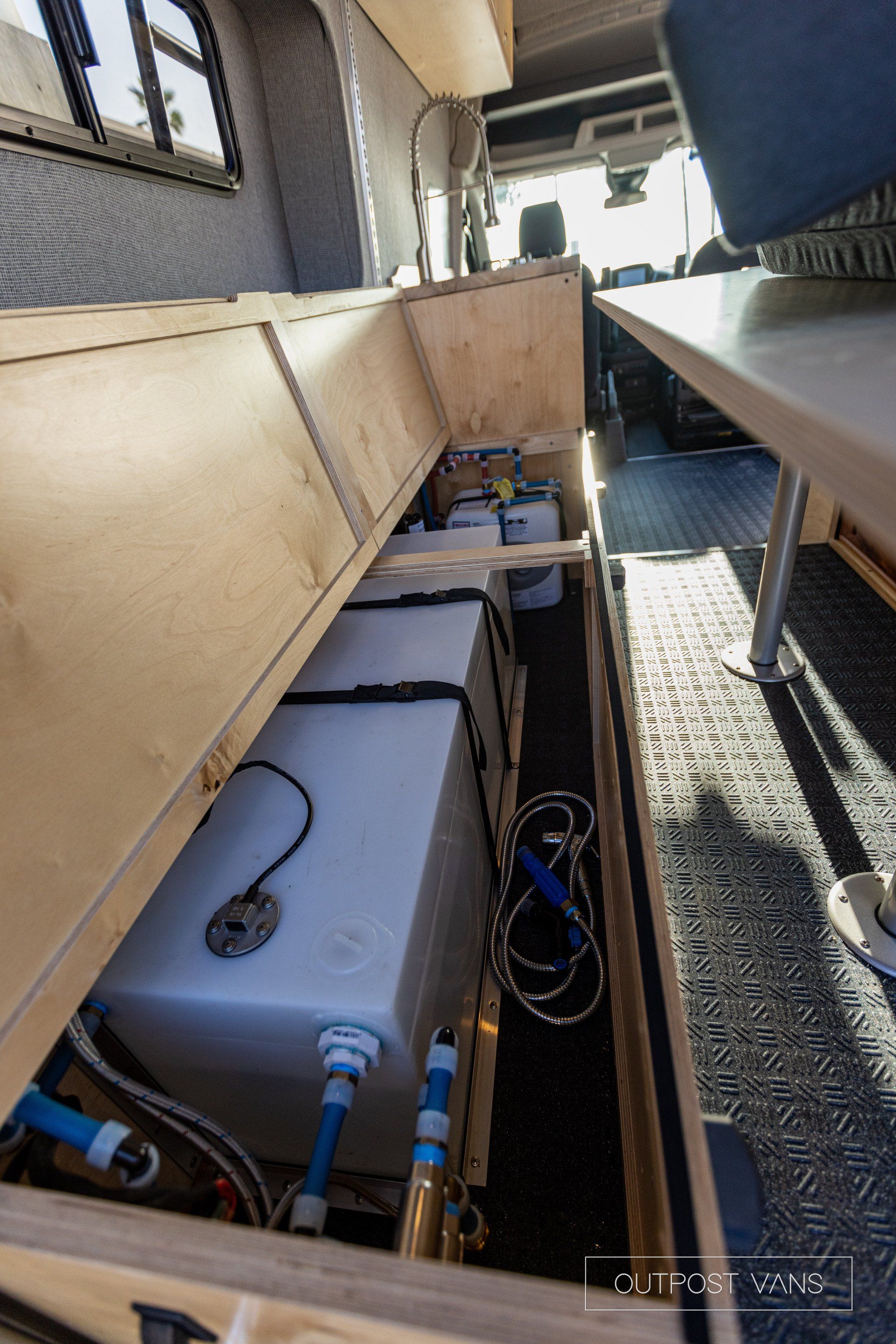 a camper van with a water tank underneath the bed .