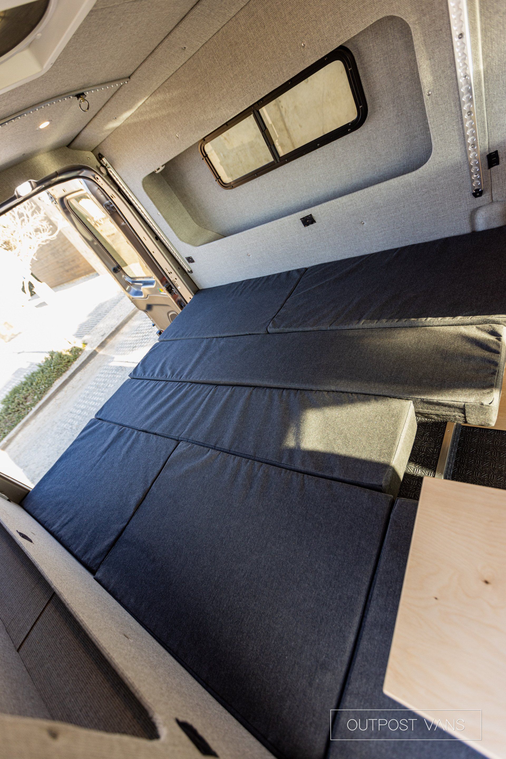 the inside of a van with a bed and a window .