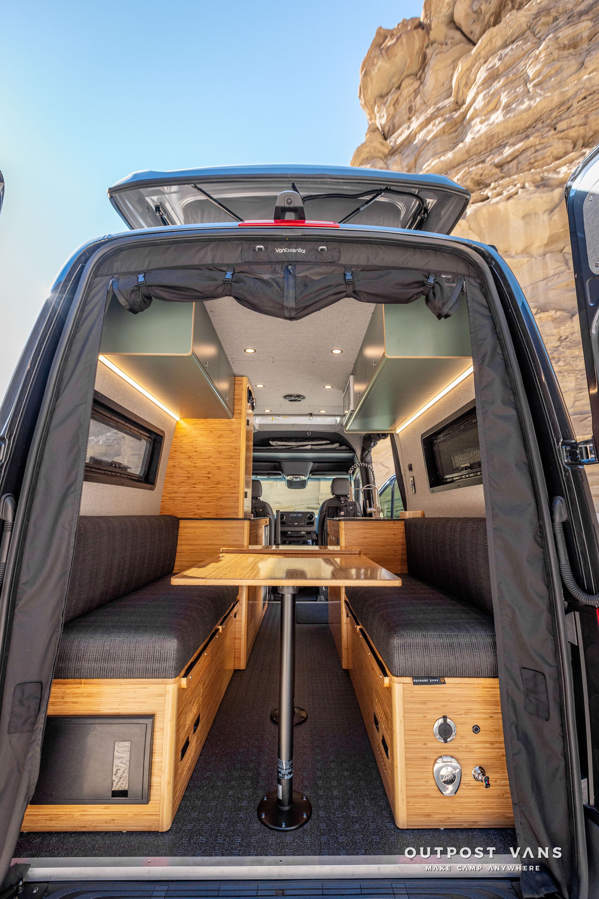 The inside of a camper van with a table and benches that convert to a bed