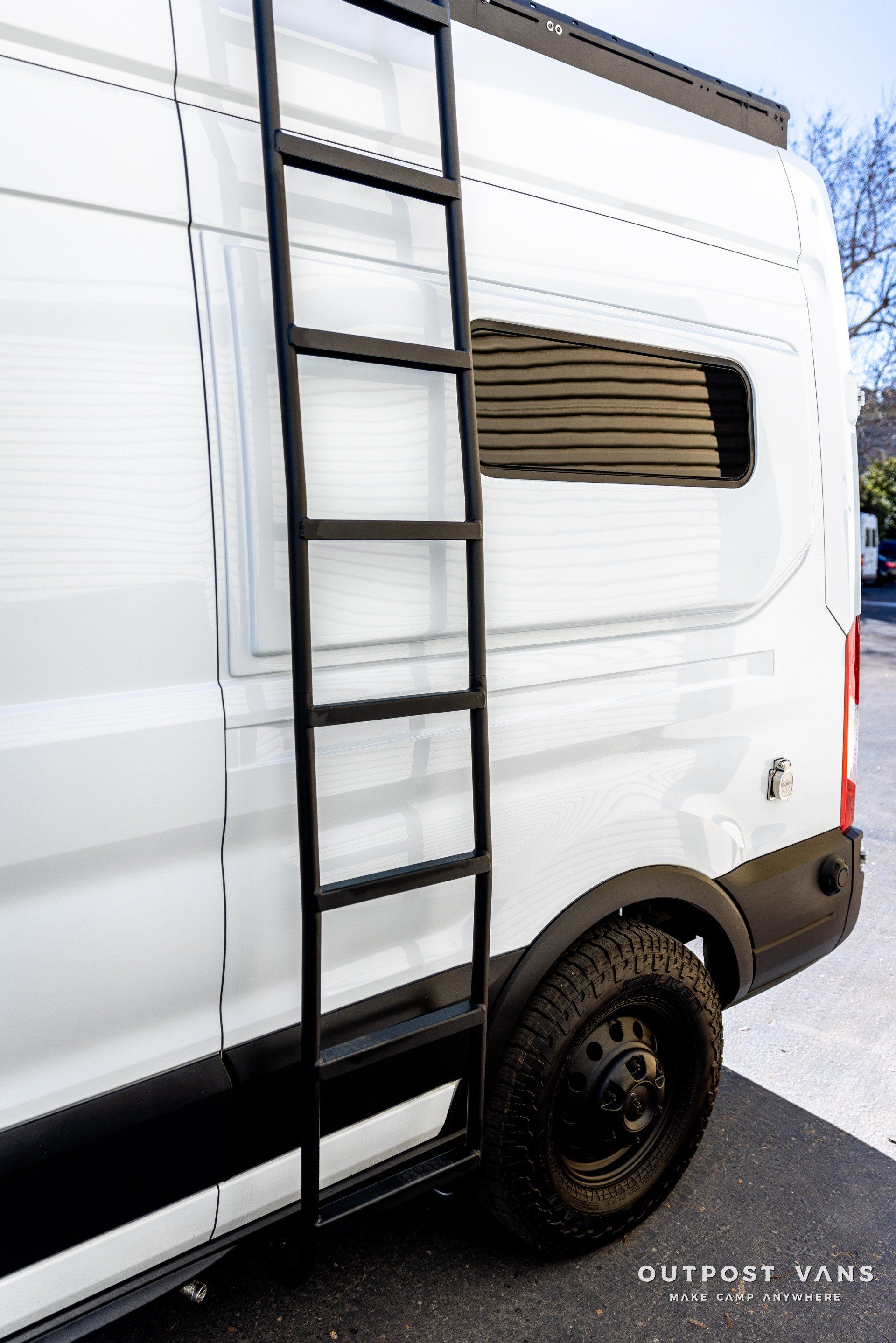 a white van with a ladder attached to the side of it .